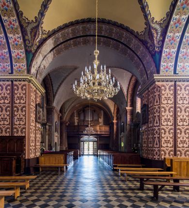 Zdjęcie nr 25: Kościół murowany, jednonawowy, z wieżą częściowo wtopioną w elewację zachodnią składający się z nawy, transeptu, zakrystii od północy z mieszczącym się na piętrze skarbcem i przystawionej od wschodu wieżyczki klatki schodowej oraz kruchty od południa. Prezbiterium dwuprzęsłowe, zamknięte trójbocznie. Nawa główna podzielona masywnymi opilastrowanymi filarami. Sklepienie prezbiterium i nawy kolebkowe z lunetami, skrzyżowania z transeptem. Od południa chór muzyczny mieszczący się między pierwszymi filarami i powyżej kruchty wejściowej. W prezbiterium okna w każdym przęśle, po każdej stronie nawy po dwa, w transepcie po trzy, w kruchcie dwa. Główne wejście od zachodu, kolejne do zakrystii i od południa. Ściany i sklepienia kościoła pokrywa polichromia złożona z geometryzujących dekoracji floralnych. 
Wschodnią elewację frontową kościoła tworzy trójosiowa, wieżowa fasada. Oś kompozycji stanowi wysunięta ryzalitowo dwukondygnacyjna wieża ze ściętymi narożami, które zaakcentowane są poprzez pilastry. Ściana czołowa wieży wypełniona w pierwszej kondygnacji wklęsłą płyciną, z portalem o wykroju prostokątnym, z odcinkiem gzymsu w zwieńczeniu. Ponad nim prostokątne okno zakończone łukiem pełnym. Kondygnacje rozdzielone za pomocą masywnego gzymsu. Druga kondygnacja wieży wypełniona analogicznie prostokątną płyciną, w którą wkomponowany jest wypukły panel w kształcie leżącego prostokąta. Nad nim okno o obramieniu i wykroju identycznym jak w kondygnacji niższej. Całość zwieńczona za pomocą gzymsu podokapowego i baniastego hełmu wieżowego o ściętych narożach, na które nałożona jest kopułka w formie cebulastej. Osie boczne cofnięte w stosunku do wysuniętej wieży i zrytmizowane podziałem ramowym. Tak jak w osi głównej pierwsza kondygnacja wypełniona jest wklęsłą płyciną w formie wydłużonego, stojącego prostokąta. Nad gzymsem trójkątny spływ przysłonięty wieżą. Elewacje boczne i tylna ukształtowane jednorodnie. Zrytmizowane podziałem ramowym i przeprute oknami umieszczonymi w prostokątnych płycinach. Ramiona transeptu oraz prezbiterium zrytmizowane są za pomocą pilastrów załamanych na narożach. Od południa do korpusu przylega niska kruchta. Prowadzi do niej wejście o wykroju prostokątnym z profilowanym w tynku portalem i z odcinkiem gzymsu w zwieńczeniu. Od północy pomiędzy prezbiterium, a ramieniem transeptu wprowadzona została piętrowa przybudówka zakrystii. W elewacji tej partii kościoła brak jest znaczących podziałów. Okna i drzwi tam się znajdujące mają formę stojącego prostokąta i pozbawione są jakichkolwiek obramień. Kościół pokryty dwuspadowym, jednokalenicowym dachem, nad zakrystią i kruchtami umieszczono daszki dwuspadowe. Wieża nakryta jest hełmem cebulastym. Całość pokryta została malowaną blachą.
