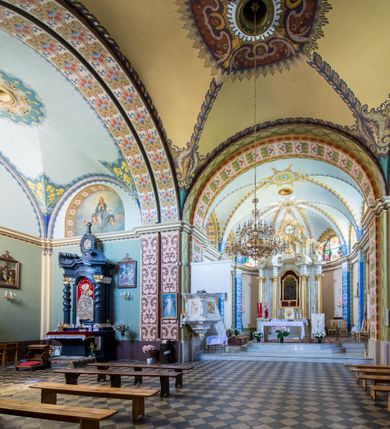 Zdjęcie nr 23: Kościół murowany, jednonawowy, z wieżą częściowo wtopioną w elewację zachodnią składający się z nawy, transeptu, zakrystii od północy z mieszczącym się na piętrze skarbcem i przystawionej od wschodu wieżyczki klatki schodowej oraz kruchty od południa. Prezbiterium dwuprzęsłowe, zamknięte trójbocznie. Nawa główna podzielona masywnymi opilastrowanymi filarami. Sklepienie prezbiterium i nawy kolebkowe z lunetami, skrzyżowania z transeptem. Od południa chór muzyczny mieszczący się między pierwszymi filarami i powyżej kruchty wejściowej. W prezbiterium okna w każdym przęśle, po każdej stronie nawy po dwa, w transepcie po trzy, w kruchcie dwa. Główne wejście od zachodu, kolejne do zakrystii i od południa. Ściany i sklepienia kościoła pokrywa polichromia złożona z geometryzujących dekoracji floralnych. 
Wschodnią elewację frontową kościoła tworzy trójosiowa, wieżowa fasada. Oś kompozycji stanowi wysunięta ryzalitowo dwukondygnacyjna wieża ze ściętymi narożami, które zaakcentowane są poprzez pilastry. Ściana czołowa wieży wypełniona w pierwszej kondygnacji wklęsłą płyciną, z portalem o wykroju prostokątnym, z odcinkiem gzymsu w zwieńczeniu. Ponad nim prostokątne okno zakończone łukiem pełnym. Kondygnacje rozdzielone za pomocą masywnego gzymsu. Druga kondygnacja wieży wypełniona analogicznie prostokątną płyciną, w którą wkomponowany jest wypukły panel w kształcie leżącego prostokąta. Nad nim okno o obramieniu i wykroju identycznym jak w kondygnacji niższej. Całość zwieńczona za pomocą gzymsu podokapowego i baniastego hełmu wieżowego o ściętych narożach, na które nałożona jest kopułka w formie cebulastej. Osie boczne cofnięte w stosunku do wysuniętej wieży i zrytmizowane podziałem ramowym. Tak jak w osi głównej pierwsza kondygnacja wypełniona jest wklęsłą płyciną w formie wydłużonego, stojącego prostokąta. Nad gzymsem trójkątny spływ przysłonięty wieżą. Elewacje boczne i tylna ukształtowane jednorodnie. Zrytmizowane podziałem ramowym i przeprute oknami umieszczonymi w prostokątnych płycinach. Ramiona transeptu oraz prezbiterium zrytmizowane są za pomocą pilastrów załamanych na narożach. Od południa do korpusu przylega niska kruchta. Prowadzi do niej wejście o wykroju prostokątnym z profilowanym w tynku portalem i z odcinkiem gzymsu w zwieńczeniu. Od północy pomiędzy prezbiterium, a ramieniem transeptu wprowadzona została piętrowa przybudówka zakrystii. W elewacji tej partii kościoła brak jest znaczących podziałów. Okna i drzwi tam się znajdujące mają formę stojącego prostokąta i pozbawione są jakichkolwiek obramień. Kościół pokryty dwuspadowym, jednokalenicowym dachem, nad zakrystią i kruchtami umieszczono daszki dwuspadowe. Wieża nakryta jest hełmem cebulastym. Całość pokryta została malowaną blachą.
