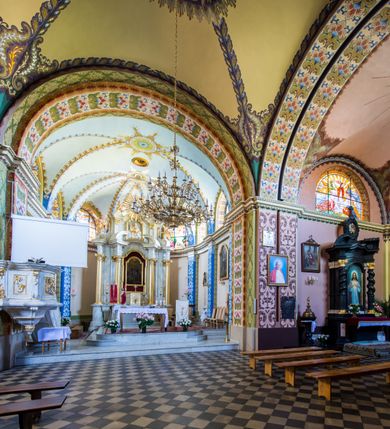 Zdjęcie nr 21: Kościół murowany, jednonawowy, z wieżą częściowo wtopioną w elewację zachodnią składający się z nawy, transeptu, zakrystii od północy z mieszczącym się na piętrze skarbcem i przystawionej od wschodu wieżyczki klatki schodowej oraz kruchty od południa. Prezbiterium dwuprzęsłowe, zamknięte trójbocznie. Nawa główna podzielona masywnymi opilastrowanymi filarami. Sklepienie prezbiterium i nawy kolebkowe z lunetami, skrzyżowania z transeptem. Od południa chór muzyczny mieszczący się między pierwszymi filarami i powyżej kruchty wejściowej. W prezbiterium okna w każdym przęśle, po każdej stronie nawy po dwa, w transepcie po trzy, w kruchcie dwa. Główne wejście od zachodu, kolejne do zakrystii i od południa. Ściany i sklepienia kościoła pokrywa polichromia złożona z geometryzujących dekoracji floralnych. 
Wschodnią elewację frontową kościoła tworzy trójosiowa, wieżowa fasada. Oś kompozycji stanowi wysunięta ryzalitowo dwukondygnacyjna wieża ze ściętymi narożami, które zaakcentowane są poprzez pilastry. Ściana czołowa wieży wypełniona w pierwszej kondygnacji wklęsłą płyciną, z portalem o wykroju prostokątnym, z odcinkiem gzymsu w zwieńczeniu. Ponad nim prostokątne okno zakończone łukiem pełnym. Kondygnacje rozdzielone za pomocą masywnego gzymsu. Druga kondygnacja wieży wypełniona analogicznie prostokątną płyciną, w którą wkomponowany jest wypukły panel w kształcie leżącego prostokąta. Nad nim okno o obramieniu i wykroju identycznym jak w kondygnacji niższej. Całość zwieńczona za pomocą gzymsu podokapowego i baniastego hełmu wieżowego o ściętych narożach, na które nałożona jest kopułka w formie cebulastej. Osie boczne cofnięte w stosunku do wysuniętej wieży i zrytmizowane podziałem ramowym. Tak jak w osi głównej pierwsza kondygnacja wypełniona jest wklęsłą płyciną w formie wydłużonego, stojącego prostokąta. Nad gzymsem trójkątny spływ przysłonięty wieżą. Elewacje boczne i tylna ukształtowane jednorodnie. Zrytmizowane podziałem ramowym i przeprute oknami umieszczonymi w prostokątnych płycinach. Ramiona transeptu oraz prezbiterium zrytmizowane są za pomocą pilastrów załamanych na narożach. Od południa do korpusu przylega niska kruchta. Prowadzi do niej wejście o wykroju prostokątnym z profilowanym w tynku portalem i z odcinkiem gzymsu w zwieńczeniu. Od północy pomiędzy prezbiterium, a ramieniem transeptu wprowadzona została piętrowa przybudówka zakrystii. W elewacji tej partii kościoła brak jest znaczących podziałów. Okna i drzwi tam się znajdujące mają formę stojącego prostokąta i pozbawione są jakichkolwiek obramień. Kościół pokryty dwuspadowym, jednokalenicowym dachem, nad zakrystią i kruchtami umieszczono daszki dwuspadowe. Wieża nakryta jest hełmem cebulastym. Całość pokryta została malowaną blachą.
