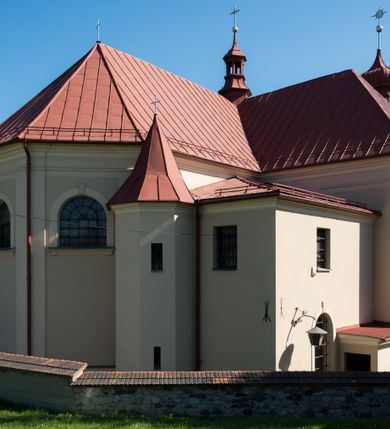 Zdjęcie nr 14: Kościół murowany, jednonawowy, z wieżą częściowo wtopioną w elewację zachodnią składający się z nawy, transeptu, zakrystii od północy z mieszczącym się na piętrze skarbcem i przystawionej od wschodu wieżyczki klatki schodowej oraz kruchty od południa. Prezbiterium dwuprzęsłowe, zamknięte trójbocznie. Nawa główna podzielona masywnymi opilastrowanymi filarami. Sklepienie prezbiterium i nawy kolebkowe z lunetami, skrzyżowania z transeptem. Od południa chór muzyczny mieszczący się między pierwszymi filarami i powyżej kruchty wejściowej. W prezbiterium okna w każdym przęśle, po każdej stronie nawy po dwa, w transepcie po trzy, w kruchcie dwa. Główne wejście od zachodu, kolejne do zakrystii i od południa. Ściany i sklepienia kościoła pokrywa polichromia złożona z geometryzujących dekoracji floralnych. 
Wschodnią elewację frontową kościoła tworzy trójosiowa, wieżowa fasada. Oś kompozycji stanowi wysunięta ryzalitowo dwukondygnacyjna wieża ze ściętymi narożami, które zaakcentowane są poprzez pilastry. Ściana czołowa wieży wypełniona w pierwszej kondygnacji wklęsłą płyciną, z portalem o wykroju prostokątnym, z odcinkiem gzymsu w zwieńczeniu. Ponad nim prostokątne okno zakończone łukiem pełnym. Kondygnacje rozdzielone za pomocą masywnego gzymsu. Druga kondygnacja wieży wypełniona analogicznie prostokątną płyciną, w którą wkomponowany jest wypukły panel w kształcie leżącego prostokąta. Nad nim okno o obramieniu i wykroju identycznym jak w kondygnacji niższej. Całość zwieńczona za pomocą gzymsu podokapowego i baniastego hełmu wieżowego o ściętych narożach, na które nałożona jest kopułka w formie cebulastej. Osie boczne cofnięte w stosunku do wysuniętej wieży i zrytmizowane podziałem ramowym. Tak jak w osi głównej pierwsza kondygnacja wypełniona jest wklęsłą płyciną w formie wydłużonego, stojącego prostokąta. Nad gzymsem trójkątny spływ przysłonięty wieżą. Elewacje boczne i tylna ukształtowane jednorodnie. Zrytmizowane podziałem ramowym i przeprute oknami umieszczonymi w prostokątnych płycinach. Ramiona transeptu oraz prezbiterium zrytmizowane są za pomocą pilastrów załamanych na narożach. Od południa do korpusu przylega niska kruchta. Prowadzi do niej wejście o wykroju prostokątnym z profilowanym w tynku portalem i z odcinkiem gzymsu w zwieńczeniu. Od północy pomiędzy prezbiterium, a ramieniem transeptu wprowadzona została piętrowa przybudówka zakrystii. W elewacji tej partii kościoła brak jest znaczących podziałów. Okna i drzwi tam się znajdujące mają formę stojącego prostokąta i pozbawione są jakichkolwiek obramień. Kościół pokryty dwuspadowym, jednokalenicowym dachem, nad zakrystią i kruchtami umieszczono daszki dwuspadowe. Wieża nakryta jest hełmem cebulastym. Całość pokryta została malowaną blachą.
