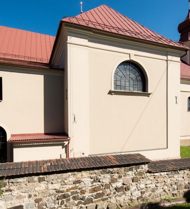 Zdjęcie nr 17: Kościół murowany, jednonawowy, z wieżą częściowo wtopioną w elewację zachodnią składający się z nawy, transeptu, zakrystii od północy z mieszczącym się na piętrze skarbcem i przystawionej od wschodu wieżyczki klatki schodowej oraz kruchty od południa. Prezbiterium dwuprzęsłowe, zamknięte trójbocznie. Nawa główna podzielona masywnymi opilastrowanymi filarami. Sklepienie prezbiterium i nawy kolebkowe z lunetami, skrzyżowania z transeptem. Od południa chór muzyczny mieszczący się między pierwszymi filarami i powyżej kruchty wejściowej. W prezbiterium okna w każdym przęśle, po każdej stronie nawy po dwa, w transepcie po trzy, w kruchcie dwa. Główne wejście od zachodu, kolejne do zakrystii i od południa. Ściany i sklepienia kościoła pokrywa polichromia złożona z geometryzujących dekoracji floralnych. 
Wschodnią elewację frontową kościoła tworzy trójosiowa, wieżowa fasada. Oś kompozycji stanowi wysunięta ryzalitowo dwukondygnacyjna wieża ze ściętymi narożami, które zaakcentowane są poprzez pilastry. Ściana czołowa wieży wypełniona w pierwszej kondygnacji wklęsłą płyciną, z portalem o wykroju prostokątnym, z odcinkiem gzymsu w zwieńczeniu. Ponad nim prostokątne okno zakończone łukiem pełnym. Kondygnacje rozdzielone za pomocą masywnego gzymsu. Druga kondygnacja wieży wypełniona analogicznie prostokątną płyciną, w którą wkomponowany jest wypukły panel w kształcie leżącego prostokąta. Nad nim okno o obramieniu i wykroju identycznym jak w kondygnacji niższej. Całość zwieńczona za pomocą gzymsu podokapowego i baniastego hełmu wieżowego o ściętych narożach, na które nałożona jest kopułka w formie cebulastej. Osie boczne cofnięte w stosunku do wysuniętej wieży i zrytmizowane podziałem ramowym. Tak jak w osi głównej pierwsza kondygnacja wypełniona jest wklęsłą płyciną w formie wydłużonego, stojącego prostokąta. Nad gzymsem trójkątny spływ przysłonięty wieżą. Elewacje boczne i tylna ukształtowane jednorodnie. Zrytmizowane podziałem ramowym i przeprute oknami umieszczonymi w prostokątnych płycinach. Ramiona transeptu oraz prezbiterium zrytmizowane są za pomocą pilastrów załamanych na narożach. Od południa do korpusu przylega niska kruchta. Prowadzi do niej wejście o wykroju prostokątnym z profilowanym w tynku portalem i z odcinkiem gzymsu w zwieńczeniu. Od północy pomiędzy prezbiterium, a ramieniem transeptu wprowadzona została piętrowa przybudówka zakrystii. W elewacji tej partii kościoła brak jest znaczących podziałów. Okna i drzwi tam się znajdujące mają formę stojącego prostokąta i pozbawione są jakichkolwiek obramień. Kościół pokryty dwuspadowym, jednokalenicowym dachem, nad zakrystią i kruchtami umieszczono daszki dwuspadowe. Wieża nakryta jest hełmem cebulastym. Całość pokryta została malowaną blachą.
