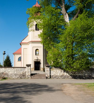 Zdjęcie nr 3: Kościół murowany, jednonawowy, z wieżą częściowo wtopioną w elewację zachodnią składający się z nawy, transeptu, zakrystii od północy z mieszczącym się na piętrze skarbcem i przystawionej od wschodu wieżyczki klatki schodowej oraz kruchty od południa. Prezbiterium dwuprzęsłowe, zamknięte trójbocznie. Nawa główna podzielona masywnymi opilastrowanymi filarami. Sklepienie prezbiterium i nawy kolebkowe z lunetami, skrzyżowania z transeptem. Od południa chór muzyczny mieszczący się między pierwszymi filarami i powyżej kruchty wejściowej. W prezbiterium okna w każdym przęśle, po każdej stronie nawy po dwa, w transepcie po trzy, w kruchcie dwa. Główne wejście od zachodu, kolejne do zakrystii i od południa. Ściany i sklepienia kościoła pokrywa polichromia złożona z geometryzujących dekoracji floralnych. 
Wschodnią elewację frontową kościoła tworzy trójosiowa, wieżowa fasada. Oś kompozycji stanowi wysunięta ryzalitowo dwukondygnacyjna wieża ze ściętymi narożami, które zaakcentowane są poprzez pilastry. Ściana czołowa wieży wypełniona w pierwszej kondygnacji wklęsłą płyciną, z portalem o wykroju prostokątnym, z odcinkiem gzymsu w zwieńczeniu. Ponad nim prostokątne okno zakończone łukiem pełnym. Kondygnacje rozdzielone za pomocą masywnego gzymsu. Druga kondygnacja wieży wypełniona analogicznie prostokątną płyciną, w którą wkomponowany jest wypukły panel w kształcie leżącego prostokąta. Nad nim okno o obramieniu i wykroju identycznym jak w kondygnacji niższej. Całość zwieńczona za pomocą gzymsu podokapowego i baniastego hełmu wieżowego o ściętych narożach, na które nałożona jest kopułka w formie cebulastej. Osie boczne cofnięte w stosunku do wysuniętej wieży i zrytmizowane podziałem ramowym. Tak jak w osi głównej pierwsza kondygnacja wypełniona jest wklęsłą płyciną w formie wydłużonego, stojącego prostokąta. Nad gzymsem trójkątny spływ przysłonięty wieżą. Elewacje boczne i tylna ukształtowane jednorodnie. Zrytmizowane podziałem ramowym i przeprute oknami umieszczonymi w prostokątnych płycinach. Ramiona transeptu oraz prezbiterium zrytmizowane są za pomocą pilastrów załamanych na narożach. Od południa do korpusu przylega niska kruchta. Prowadzi do niej wejście o wykroju prostokątnym z profilowanym w tynku portalem i z odcinkiem gzymsu w zwieńczeniu. Od północy pomiędzy prezbiterium, a ramieniem transeptu wprowadzona została piętrowa przybudówka zakrystii. W elewacji tej partii kościoła brak jest znaczących podziałów. Okna i drzwi tam się znajdujące mają formę stojącego prostokąta i pozbawione są jakichkolwiek obramień. Kościół pokryty dwuspadowym, jednokalenicowym dachem, nad zakrystią i kruchtami umieszczono daszki dwuspadowe. Wieża nakryta jest hełmem cebulastym. Całość pokryta została malowaną blachą.
