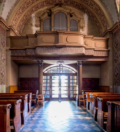 Zdjęcie nr 27: Kościół murowany, jednonawowy, z wieżą częściowo wtopioną w elewację zachodnią składający się z nawy, transeptu, zakrystii od północy z mieszczącym się na piętrze skarbcem i przystawionej od wschodu wieżyczki klatki schodowej oraz kruchty od południa. Prezbiterium dwuprzęsłowe, zamknięte trójbocznie. Nawa główna podzielona masywnymi opilastrowanymi filarami. Sklepienie prezbiterium i nawy kolebkowe z lunetami, skrzyżowania z transeptem. Od południa chór muzyczny mieszczący się między pierwszymi filarami i powyżej kruchty wejściowej. W prezbiterium okna w każdym przęśle, po każdej stronie nawy po dwa, w transepcie po trzy, w kruchcie dwa. Główne wejście od zachodu, kolejne do zakrystii i od południa. Ściany i sklepienia kościoła pokrywa polichromia złożona z geometryzujących dekoracji floralnych. 
Wschodnią elewację frontową kościoła tworzy trójosiowa, wieżowa fasada. Oś kompozycji stanowi wysunięta ryzalitowo dwukondygnacyjna wieża ze ściętymi narożami, które zaakcentowane są poprzez pilastry. Ściana czołowa wieży wypełniona w pierwszej kondygnacji wklęsłą płyciną, z portalem o wykroju prostokątnym, z odcinkiem gzymsu w zwieńczeniu. Ponad nim prostokątne okno zakończone łukiem pełnym. Kondygnacje rozdzielone za pomocą masywnego gzymsu. Druga kondygnacja wieży wypełniona analogicznie prostokątną płyciną, w którą wkomponowany jest wypukły panel w kształcie leżącego prostokąta. Nad nim okno o obramieniu i wykroju identycznym jak w kondygnacji niższej. Całość zwieńczona za pomocą gzymsu podokapowego i baniastego hełmu wieżowego o ściętych narożach, na które nałożona jest kopułka w formie cebulastej. Osie boczne cofnięte w stosunku do wysuniętej wieży i zrytmizowane podziałem ramowym. Tak jak w osi głównej pierwsza kondygnacja wypełniona jest wklęsłą płyciną w formie wydłużonego, stojącego prostokąta. Nad gzymsem trójkątny spływ przysłonięty wieżą. Elewacje boczne i tylna ukształtowane jednorodnie. Zrytmizowane podziałem ramowym i przeprute oknami umieszczonymi w prostokątnych płycinach. Ramiona transeptu oraz prezbiterium zrytmizowane są za pomocą pilastrów załamanych na narożach. Od południa do korpusu przylega niska kruchta. Prowadzi do niej wejście o wykroju prostokątnym z profilowanym w tynku portalem i z odcinkiem gzymsu w zwieńczeniu. Od północy pomiędzy prezbiterium, a ramieniem transeptu wprowadzona została piętrowa przybudówka zakrystii. W elewacji tej partii kościoła brak jest znaczących podziałów. Okna i drzwi tam się znajdujące mają formę stojącego prostokąta i pozbawione są jakichkolwiek obramień. Kościół pokryty dwuspadowym, jednokalenicowym dachem, nad zakrystią i kruchtami umieszczono daszki dwuspadowe. Wieża nakryta jest hełmem cebulastym. Całość pokryta została malowaną blachą.
