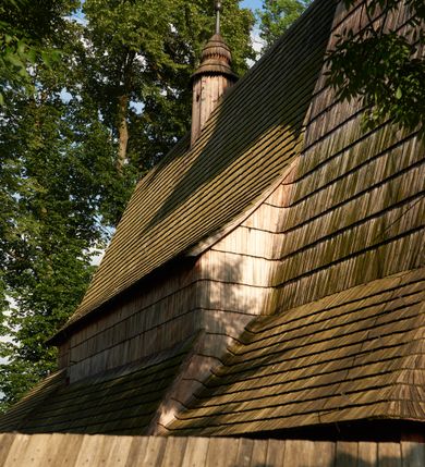 Zdjęcie nr 13: Orientowany, jednoprzestrzenny, nawa na rzucie prostokąta, z węższym, prostokątnym prezbiterium, przy którym od północy wąska zakrystia. Od zachodu przy nawie wieża na rzucie kwadratu, od południa kruchta. Wnętrze nakryte stropem, w nawie z zaskrzynieniem. Portale zachodni i do zakrystii ostrołukowe, fazowane; portal południowy zamknięty łukiem kotarowym. Okna prostokątne, w prezbiterium od południa okno bliźnie, od wschodu zamknięte łukiem kotarowym.  Wokół podcienia, obecnie zaszalowane. Więźba dachowa jętkowa, ze znakami montażowymi.  Dach nad nawą i prezbiterium jednokalenicowy, dwuspadowy, nad nawą z połaciami przedłużonymi na zaskrzynienia i od północy nad zakrystię. Na kalenicy wieżyczka na sygnaturkę z baniastym hełmem.  Wieża o ścianach pochyłych, z nadwieszoną izbicą, zwieńczona ostrosłupowym hełmem. Wokół kościoła ogrodzenie belek układanych na zrąb, z dwiema bramkami. 