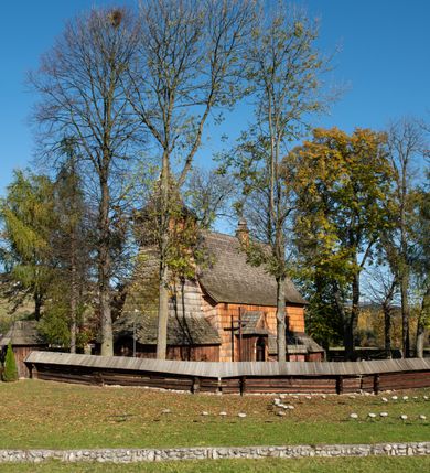 Zdjęcie nr 23: Orientowany, jednoprzestrzenny, nawa na rzucie prostokąta, z węższym, prostokątnym prezbiterium, przy którym od północy wąska zakrystia. Od zachodu przy nawie wieża na rzucie kwadratu, od południa kruchta. Wnętrze nakryte stropem, w nawie z zaskrzynieniem. Portale zachodni i do zakrystii ostrołukowe, fazowane; portal południowy zamknięty łukiem kotarowym. Okna prostokątne, w prezbiterium od południa okno bliźnie, od wschodu zamknięte łukiem kotarowym.  Wokół podcienia, obecnie zaszalowane. Więźba dachowa jętkowa, ze znakami montażowymi.  Dach nad nawą i prezbiterium jednokalenicowy, dwuspadowy, nad nawą z połaciami przedłużonymi na zaskrzynienia i od północy nad zakrystię. Na kalenicy wieżyczka na sygnaturkę z baniastym hełmem.  Wieża o ścianach pochyłych, z nadwieszoną izbicą, zwieńczona ostrosłupowym hełmem. Wokół kościoła ogrodzenie belek układanych na zrąb, z dwiema bramkami. 