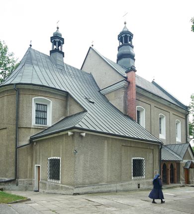 Zdjęcie nr 3: Kościół murowany, orientowany, jednonawowy (z dodatkową przestrzenią od południa powstałą w wyniku połączenia trzech kaplic), z półkoliście zamkniętym prezbiterium, z prostokątną zakrystią od północy, z kruchtą na osi nawy głównej oraz drugą od północy; między zakrystią a kruchtą północną babiniec. 
Nawa szersza od prezbiterium, prostokątna, trójprzęsłowa, ze sklepieniem kolebkowym z lunetami na gurtach. Od zachodu chór muzyczny wsparty na kolumnach. Ściany nawy podzielone zdwojonymi pilastrami, między którymi nisze arkadowe, od południa półokrągłe arkady łączące nawę główną z nawą boczną. Partię ścian od sklepienia oddziela pełne belkowanie wyłamane na osi pilastrów, które jest kontynuowane w przekrytym sklepieniem kolebkowym z lunetami prezbiterium.  
W partii przyziemia oraz sklepienia prostokątne okna w rozglifionych obramieniach zamkniętych łukiem odcinkowym, na osi prezbiterium owalne. Od zachodu oraz od południa drzwi zamknięte łukiem odcinkowym. 
Fasada trójosiowa, dwukondygnacyjna, zwieńczona trójkątnym przyczółkiem, poprzedzona jednokondygnacyjną kruchtą, do której wchodzi się po sześciostopniowych schodach. Osie rozdzielone są pojedynczymi lub zdwojonymi pilastrami, kondygnacje dzieli bogato profilowane belkowanie. W kruchcie drzwi o wykroju prostokąta zamknięte łukiem odcinkowym, okna w osiach bocznych o identycznym jak drzwi wykroju; okulus w szczycie. W osi środkowej drugiej kondygnacji fasady okno prostokątne, zamknięte łukiem odcinkowym, a u szczytu okulus. 
Na elewacjach kontynuowany jest gzyms oddzielający drugą kondygnację i partię dachu, pionowe podziały utworzone zostały przez lizeny. 
Nawa główna oraz kruchty nakryte dachami dwuspadowymi, część nawy bocznej, zakrystia oraz babiniec jednospadowymi, druga część nawy bocznej trójspadowym, zakrystia dwuspadowym zamkniętym półkoliście. Dwie wieżyczki na sygnaturki: jedna nad nawą główną, druga, mniejsza nad prezbiterium. Obie przeprute arkadami, zwieńczone kopułami z kulą i krzyżem. 
Do najważniejszych elementów wyposażenia należą: ołtarz główny późnobarokowy z obrazem Przemienienia Pańskiego przywieziony z Rzymu w 1723 roku, dwa regencyjne ołtarze boczne z barokowymi obrazami Matki Boskiej z Dzieciątkiem oraz św. Katarzyny, oba ozdobione sukienkami oraz obraz z przedstawieniem św. Józefa, pochodzący z trzeciego ołtarza wisi teraz na ścianie nawy głównej. 
