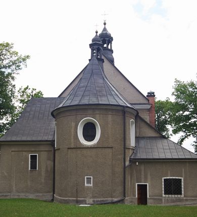 Zdjęcie nr 4: Kościół murowany, orientowany, jednonawowy (z dodatkową przestrzenią od południa powstałą w wyniku połączenia trzech kaplic), z półkoliście zamkniętym prezbiterium, z prostokątną zakrystią od północy, z kruchtą na osi nawy głównej oraz drugą od północy; między zakrystią a kruchtą północną babiniec. 
Nawa szersza od prezbiterium, prostokątna, trójprzęsłowa, ze sklepieniem kolebkowym z lunetami na gurtach. Od zachodu chór muzyczny wsparty na kolumnach. Ściany nawy podzielone zdwojonymi pilastrami, między którymi nisze arkadowe, od południa półokrągłe arkady łączące nawę główną z nawą boczną. Partię ścian od sklepienia oddziela pełne belkowanie wyłamane na osi pilastrów, które jest kontynuowane w przekrytym sklepieniem kolebkowym z lunetami prezbiterium.  
W partii przyziemia oraz sklepienia prostokątne okna w rozglifionych obramieniach zamkniętych łukiem odcinkowym, na osi prezbiterium owalne. Od zachodu oraz od południa drzwi zamknięte łukiem odcinkowym. 
Fasada trójosiowa, dwukondygnacyjna, zwieńczona trójkątnym przyczółkiem, poprzedzona jednokondygnacyjną kruchtą, do której wchodzi się po sześciostopniowych schodach. Osie rozdzielone są pojedynczymi lub zdwojonymi pilastrami, kondygnacje dzieli bogato profilowane belkowanie. W kruchcie drzwi o wykroju prostokąta zamknięte łukiem odcinkowym, okna w osiach bocznych o identycznym jak drzwi wykroju; okulus w szczycie. W osi środkowej drugiej kondygnacji fasady okno prostokątne, zamknięte łukiem odcinkowym, a u szczytu okulus. 
Na elewacjach kontynuowany jest gzyms oddzielający drugą kondygnację i partię dachu, pionowe podziały utworzone zostały przez lizeny. 
Nawa główna oraz kruchty nakryte dachami dwuspadowymi, część nawy bocznej, zakrystia oraz babiniec jednospadowymi, druga część nawy bocznej trójspadowym, zakrystia dwuspadowym zamkniętym półkoliście. Dwie wieżyczki na sygnaturki: jedna nad nawą główną, druga, mniejsza nad prezbiterium. Obie przeprute arkadami, zwieńczone kopułami z kulą i krzyżem. 
Do najważniejszych elementów wyposażenia należą: ołtarz główny późnobarokowy z obrazem Przemienienia Pańskiego przywieziony z Rzymu w 1723 roku, dwa regencyjne ołtarze boczne z barokowymi obrazami Matki Boskiej z Dzieciątkiem oraz św. Katarzyny, oba ozdobione sukienkami oraz obraz z przedstawieniem św. Józefa, pochodzący z trzeciego ołtarza wisi teraz na ścianie nawy głównej. 
