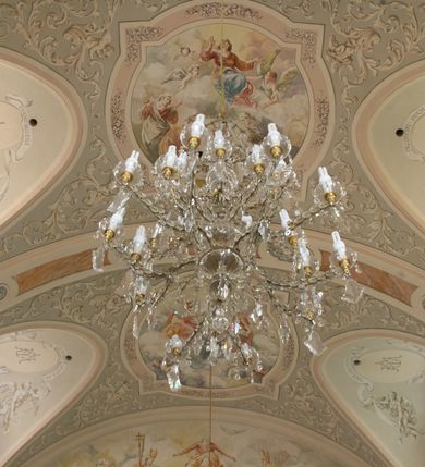 Zdjęcie nr 10: Kościół murowany, orientowany, jednonawowy (z dodatkową przestrzenią od południa powstałą w wyniku połączenia trzech kaplic), z półkoliście zamkniętym prezbiterium, z prostokątną zakrystią od północy, z kruchtą na osi nawy głównej oraz drugą od północy; między zakrystią a kruchtą północną babiniec. 
Nawa szersza od prezbiterium, prostokątna, trójprzęsłowa, ze sklepieniem kolebkowym z lunetami na gurtach. Od zachodu chór muzyczny wsparty na kolumnach. Ściany nawy podzielone zdwojonymi pilastrami, między którymi nisze arkadowe, od południa półokrągłe arkady łączące nawę główną z nawą boczną. Partię ścian od sklepienia oddziela pełne belkowanie wyłamane na osi pilastrów, które jest kontynuowane w przekrytym sklepieniem kolebkowym z lunetami prezbiterium.  
W partii przyziemia oraz sklepienia prostokątne okna w rozglifionych obramieniach zamkniętych łukiem odcinkowym, na osi prezbiterium owalne. Od zachodu oraz od południa drzwi zamknięte łukiem odcinkowym. 
Fasada trójosiowa, dwukondygnacyjna, zwieńczona trójkątnym przyczółkiem, poprzedzona jednokondygnacyjną kruchtą, do której wchodzi się po sześciostopniowych schodach. Osie rozdzielone są pojedynczymi lub zdwojonymi pilastrami, kondygnacje dzieli bogato profilowane belkowanie. W kruchcie drzwi o wykroju prostokąta zamknięte łukiem odcinkowym, okna w osiach bocznych o identycznym jak drzwi wykroju; okulus w szczycie. W osi środkowej drugiej kondygnacji fasady okno prostokątne, zamknięte łukiem odcinkowym, a u szczytu okulus. 
Na elewacjach kontynuowany jest gzyms oddzielający drugą kondygnację i partię dachu, pionowe podziały utworzone zostały przez lizeny. 
Nawa główna oraz kruchty nakryte dachami dwuspadowymi, część nawy bocznej, zakrystia oraz babiniec jednospadowymi, druga część nawy bocznej trójspadowym, zakrystia dwuspadowym zamkniętym półkoliście. Dwie wieżyczki na sygnaturki: jedna nad nawą główną, druga, mniejsza nad prezbiterium. Obie przeprute arkadami, zwieńczone kopułami z kulą i krzyżem. 
Do najważniejszych elementów wyposażenia należą: ołtarz główny późnobarokowy z obrazem Przemienienia Pańskiego przywieziony z Rzymu w 1723 roku, dwa regencyjne ołtarze boczne z barokowymi obrazami Matki Boskiej z Dzieciątkiem oraz św. Katarzyny, oba ozdobione sukienkami oraz obraz z przedstawieniem św. Józefa, pochodzący z trzeciego ołtarza wisi teraz na ścianie nawy głównej. 
