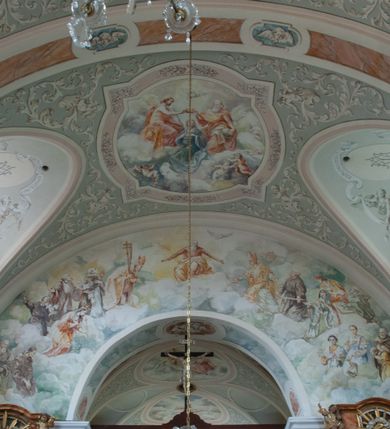 Zdjęcie nr 17: Kościół murowany, orientowany, jednonawowy (z dodatkową przestrzenią od południa powstałą w wyniku połączenia trzech kaplic), z półkoliście zamkniętym prezbiterium, z prostokątną zakrystią od północy, z kruchtą na osi nawy głównej oraz drugą od północy; między zakrystią a kruchtą północną babiniec. 
Nawa szersza od prezbiterium, prostokątna, trójprzęsłowa, ze sklepieniem kolebkowym z lunetami na gurtach. Od zachodu chór muzyczny wsparty na kolumnach. Ściany nawy podzielone zdwojonymi pilastrami, między którymi nisze arkadowe, od południa półokrągłe arkady łączące nawę główną z nawą boczną. Partię ścian od sklepienia oddziela pełne belkowanie wyłamane na osi pilastrów, które jest kontynuowane w przekrytym sklepieniem kolebkowym z lunetami prezbiterium.  
W partii przyziemia oraz sklepienia prostokątne okna w rozglifionych obramieniach zamkniętych łukiem odcinkowym, na osi prezbiterium owalne. Od zachodu oraz od południa drzwi zamknięte łukiem odcinkowym. 
Fasada trójosiowa, dwukondygnacyjna, zwieńczona trójkątnym przyczółkiem, poprzedzona jednokondygnacyjną kruchtą, do której wchodzi się po sześciostopniowych schodach. Osie rozdzielone są pojedynczymi lub zdwojonymi pilastrami, kondygnacje dzieli bogato profilowane belkowanie. W kruchcie drzwi o wykroju prostokąta zamknięte łukiem odcinkowym, okna w osiach bocznych o identycznym jak drzwi wykroju; okulus w szczycie. W osi środkowej drugiej kondygnacji fasady okno prostokątne, zamknięte łukiem odcinkowym, a u szczytu okulus. 
Na elewacjach kontynuowany jest gzyms oddzielający drugą kondygnację i partię dachu, pionowe podziały utworzone zostały przez lizeny. 
Nawa główna oraz kruchty nakryte dachami dwuspadowymi, część nawy bocznej, zakrystia oraz babiniec jednospadowymi, druga część nawy bocznej trójspadowym, zakrystia dwuspadowym zamkniętym półkoliście. Dwie wieżyczki na sygnaturki: jedna nad nawą główną, druga, mniejsza nad prezbiterium. Obie przeprute arkadami, zwieńczone kopułami z kulą i krzyżem. 
Do najważniejszych elementów wyposażenia należą: ołtarz główny późnobarokowy z obrazem Przemienienia Pańskiego przywieziony z Rzymu w 1723 roku, dwa regencyjne ołtarze boczne z barokowymi obrazami Matki Boskiej z Dzieciątkiem oraz św. Katarzyny, oba ozdobione sukienkami oraz obraz z przedstawieniem św. Józefa, pochodzący z trzeciego ołtarza wisi teraz na ścianie nawy głównej. 
