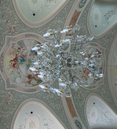 Zdjęcie nr 18: Kościół murowany, orientowany, jednonawowy (z dodatkową przestrzenią od południa powstałą w wyniku połączenia trzech kaplic), z półkoliście zamkniętym prezbiterium, z prostokątną zakrystią od północy, z kruchtą na osi nawy głównej oraz drugą od północy; między zakrystią a kruchtą północną babiniec. 
Nawa szersza od prezbiterium, prostokątna, trójprzęsłowa, ze sklepieniem kolebkowym z lunetami na gurtach. Od zachodu chór muzyczny wsparty na kolumnach. Ściany nawy podzielone zdwojonymi pilastrami, między którymi nisze arkadowe, od południa półokrągłe arkady łączące nawę główną z nawą boczną. Partię ścian od sklepienia oddziela pełne belkowanie wyłamane na osi pilastrów, które jest kontynuowane w przekrytym sklepieniem kolebkowym z lunetami prezbiterium.  
W partii przyziemia oraz sklepienia prostokątne okna w rozglifionych obramieniach zamkniętych łukiem odcinkowym, na osi prezbiterium owalne. Od zachodu oraz od południa drzwi zamknięte łukiem odcinkowym. 
Fasada trójosiowa, dwukondygnacyjna, zwieńczona trójkątnym przyczółkiem, poprzedzona jednokondygnacyjną kruchtą, do której wchodzi się po sześciostopniowych schodach. Osie rozdzielone są pojedynczymi lub zdwojonymi pilastrami, kondygnacje dzieli bogato profilowane belkowanie. W kruchcie drzwi o wykroju prostokąta zamknięte łukiem odcinkowym, okna w osiach bocznych o identycznym jak drzwi wykroju; okulus w szczycie. W osi środkowej drugiej kondygnacji fasady okno prostokątne, zamknięte łukiem odcinkowym, a u szczytu okulus. 
Na elewacjach kontynuowany jest gzyms oddzielający drugą kondygnację i partię dachu, pionowe podziały utworzone zostały przez lizeny. 
Nawa główna oraz kruchty nakryte dachami dwuspadowymi, część nawy bocznej, zakrystia oraz babiniec jednospadowymi, druga część nawy bocznej trójspadowym, zakrystia dwuspadowym zamkniętym półkoliście. Dwie wieżyczki na sygnaturki: jedna nad nawą główną, druga, mniejsza nad prezbiterium. Obie przeprute arkadami, zwieńczone kopułami z kulą i krzyżem. 
Do najważniejszych elementów wyposażenia należą: ołtarz główny późnobarokowy z obrazem Przemienienia Pańskiego przywieziony z Rzymu w 1723 roku, dwa regencyjne ołtarze boczne z barokowymi obrazami Matki Boskiej z Dzieciątkiem oraz św. Katarzyny, oba ozdobione sukienkami oraz obraz z przedstawieniem św. Józefa, pochodzący z trzeciego ołtarza wisi teraz na ścianie nawy głównej. 
