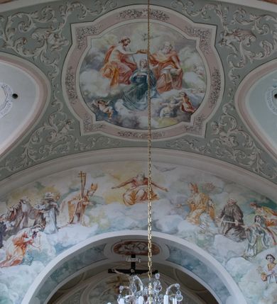 Zdjęcie nr 20: Kościół murowany, orientowany, jednonawowy (z dodatkową przestrzenią od południa powstałą w wyniku połączenia trzech kaplic), z półkoliście zamkniętym prezbiterium, z prostokątną zakrystią od północy, z kruchtą na osi nawy głównej oraz drugą od północy; między zakrystią a kruchtą północną babiniec. 
Nawa szersza od prezbiterium, prostokątna, trójprzęsłowa, ze sklepieniem kolebkowym z lunetami na gurtach. Od zachodu chór muzyczny wsparty na kolumnach. Ściany nawy podzielone zdwojonymi pilastrami, między którymi nisze arkadowe, od południa półokrągłe arkady łączące nawę główną z nawą boczną. Partię ścian od sklepienia oddziela pełne belkowanie wyłamane na osi pilastrów, które jest kontynuowane w przekrytym sklepieniem kolebkowym z lunetami prezbiterium.  
W partii przyziemia oraz sklepienia prostokątne okna w rozglifionych obramieniach zamkniętych łukiem odcinkowym, na osi prezbiterium owalne. Od zachodu oraz od południa drzwi zamknięte łukiem odcinkowym. 
Fasada trójosiowa, dwukondygnacyjna, zwieńczona trójkątnym przyczółkiem, poprzedzona jednokondygnacyjną kruchtą, do której wchodzi się po sześciostopniowych schodach. Osie rozdzielone są pojedynczymi lub zdwojonymi pilastrami, kondygnacje dzieli bogato profilowane belkowanie. W kruchcie drzwi o wykroju prostokąta zamknięte łukiem odcinkowym, okna w osiach bocznych o identycznym jak drzwi wykroju; okulus w szczycie. W osi środkowej drugiej kondygnacji fasady okno prostokątne, zamknięte łukiem odcinkowym, a u szczytu okulus. 
Na elewacjach kontynuowany jest gzyms oddzielający drugą kondygnację i partię dachu, pionowe podziały utworzone zostały przez lizeny. 
Nawa główna oraz kruchty nakryte dachami dwuspadowymi, część nawy bocznej, zakrystia oraz babiniec jednospadowymi, druga część nawy bocznej trójspadowym, zakrystia dwuspadowym zamkniętym półkoliście. Dwie wieżyczki na sygnaturki: jedna nad nawą główną, druga, mniejsza nad prezbiterium. Obie przeprute arkadami, zwieńczone kopułami z kulą i krzyżem. 
Do najważniejszych elementów wyposażenia należą: ołtarz główny późnobarokowy z obrazem Przemienienia Pańskiego przywieziony z Rzymu w 1723 roku, dwa regencyjne ołtarze boczne z barokowymi obrazami Matki Boskiej z Dzieciątkiem oraz św. Katarzyny, oba ozdobione sukienkami oraz obraz z przedstawieniem św. Józefa, pochodzący z trzeciego ołtarza wisi teraz na ścianie nawy głównej. 
