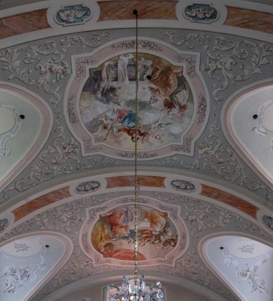 Zdjęcie nr 21: Kościół murowany, orientowany, jednonawowy (z dodatkową przestrzenią od południa powstałą w wyniku połączenia trzech kaplic), z półkoliście zamkniętym prezbiterium, z prostokątną zakrystią od północy, z kruchtą na osi nawy głównej oraz drugą od północy; między zakrystią a kruchtą północną babiniec. 
Nawa szersza od prezbiterium, prostokątna, trójprzęsłowa, ze sklepieniem kolebkowym z lunetami na gurtach. Od zachodu chór muzyczny wsparty na kolumnach. Ściany nawy podzielone zdwojonymi pilastrami, między którymi nisze arkadowe, od południa półokrągłe arkady łączące nawę główną z nawą boczną. Partię ścian od sklepienia oddziela pełne belkowanie wyłamane na osi pilastrów, które jest kontynuowane w przekrytym sklepieniem kolebkowym z lunetami prezbiterium.  
W partii przyziemia oraz sklepienia prostokątne okna w rozglifionych obramieniach zamkniętych łukiem odcinkowym, na osi prezbiterium owalne. Od zachodu oraz od południa drzwi zamknięte łukiem odcinkowym. 
Fasada trójosiowa, dwukondygnacyjna, zwieńczona trójkątnym przyczółkiem, poprzedzona jednokondygnacyjną kruchtą, do której wchodzi się po sześciostopniowych schodach. Osie rozdzielone są pojedynczymi lub zdwojonymi pilastrami, kondygnacje dzieli bogato profilowane belkowanie. W kruchcie drzwi o wykroju prostokąta zamknięte łukiem odcinkowym, okna w osiach bocznych o identycznym jak drzwi wykroju; okulus w szczycie. W osi środkowej drugiej kondygnacji fasady okno prostokątne, zamknięte łukiem odcinkowym, a u szczytu okulus. 
Na elewacjach kontynuowany jest gzyms oddzielający drugą kondygnację i partię dachu, pionowe podziały utworzone zostały przez lizeny. 
Nawa główna oraz kruchty nakryte dachami dwuspadowymi, część nawy bocznej, zakrystia oraz babiniec jednospadowymi, druga część nawy bocznej trójspadowym, zakrystia dwuspadowym zamkniętym półkoliście. Dwie wieżyczki na sygnaturki: jedna nad nawą główną, druga, mniejsza nad prezbiterium. Obie przeprute arkadami, zwieńczone kopułami z kulą i krzyżem. 
Do najważniejszych elementów wyposażenia należą: ołtarz główny późnobarokowy z obrazem Przemienienia Pańskiego przywieziony z Rzymu w 1723 roku, dwa regencyjne ołtarze boczne z barokowymi obrazami Matki Boskiej z Dzieciątkiem oraz św. Katarzyny, oba ozdobione sukienkami oraz obraz z przedstawieniem św. Józefa, pochodzący z trzeciego ołtarza wisi teraz na ścianie nawy głównej. 
