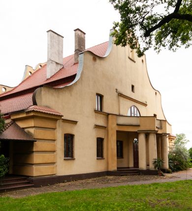 Zdjęcie nr 3: Plebania jest usytuowana po południowej stronie kościoła; poza obrębem ogrodzenia. Budyneka zwrócony frontem ku północy, parterowy z mieszkalnym poddaszem, częściowo podpiwniczony. Na rzucie szerokiego prostokąta, układ wnętrza osiowy, w ogólnej dyspozycji trójdzielny, dwutraktowy; od zachodu trzytraktowy. Przy elewacji wschodniej niska przybudówka. Na osi budynku od północy sień, od południa salon. W części wschodniej cztery pomieszczenia w tym trzy mieszkalne oraz kancelaria parafialna dostępna osobnym wejściem przez przybudówkę. W części zachodniej sześć pomieszczeń, w tym kuchnia, spiżarnia, sanitariaty, wewnętrzny korytarz oraz nieregularne pomieszczenie klatki schodowej na poddasze. Na poddaszu sześć pomieszczeń. W pomieszczeniach sufity. W salonie bogato zdobiony strop kasetonowy z licznymi inskrypcjami m.in.: łacińskim wersetem, datą budowy – 1922 roku, oraz zapisy dotyczące fundacji kościoła w 1223 roku, założenia kamienia węgielnego odbudowy kościoła po zniszczeniach wojennych w 1923 roku, objęcia rządów nad diecezją kielecką przez arcybiskupa Sapiechę w 1925 roku, oraz wystawienia przy kościele kaplicy Matki Boskiej Bolesnej i budowy plebanii staraniem księdza Boratyńskiego. W pomieszczeniach piece kaflowe; w salonie ozdobny. Elewacje zewnętrze tynkowane na żółto, na cokole, z narożami ujętymi wydatnym boniowaniem. Okna niewielkie zamknięte łukami odcinkowymi, w elewacjach dłuższych boków ponad oknami parteru odcinki gzymsu okapowego. W obu dłuższych elewacjach szerokie szczyty o fantazyjnej, falistej linii z sześcioma kolistymi prześwitami wzdłuż krawędzi; pośrodku po obu stronach duże półkoliste okna, w części środkowej zawierające wyjścia na balkony: frontowy wsparty na czterech kolumnach i tylny nadwieszony, mały, niedokończony. Po bokach okien półkolistych po jednym oknie, ponadto powyżej z obu stron po jednym okienku strychowym; w zwieńczeniu szczytu od północy pusta płycina zamknięta półkoliście. Dach dwuspadowy, łamany, kryty dachówką. 


Inskrypcje ze stropu kasetonowego: Inskrypcje ze stropu kasetonowego: 1) Na ramach kasetonów: COMES SIT IPSE DEUS / INDEQUE MIGRANTI / A(NNO) D(OMINI) 1922 / BENEDICTO QUOQUE MANENTI / SALUS HIC INTRANTI; 2) W płycinach: 1. Wystawienie kaplicy Matki Boskiej Bolesnej i wybudowanie plebanji dla wielu- zgorszeniem, dla wielu - zrozumieniem, dla mnie świętym trudem, jako usprawiedliwienie moje przed Bogiem. Prob(oszcz) Par(afii) Wawrzeńczcyce ks(iądz) Zygmunt Boratyński. 1919-1932; 2. Iwo Odrowąż Biskup Krakowski Fundator Kościoła św. Marji Magdaleny w Wawrzeńczycach 1223.; 3. Książę Adam Stefan Sapieha Arcybiskup – Metropolita Krakowski objął rządy na parafją Wawrzeńczyce diecezji Kieleckiej 1925 r (oku); 4. J(ego) E(kscelencja) X(iądz) Augustyn Łosiński Biskup Kielecki założył kamień węgielny pod odbudowę kościoła dn(ia) 22 lipca 1923 r(oku) w uroczystość 700lecia kościoła par(afialnego) w Wawrzeńczycach zniszczonego przez wojnę w r(oku) 1914. 1223-1923.