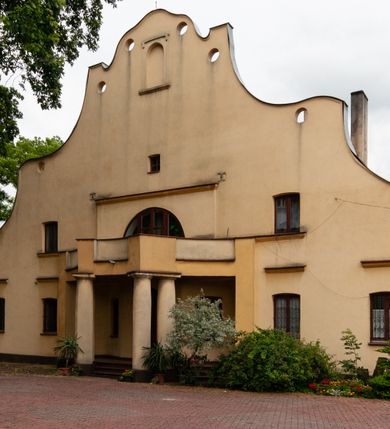 Zdjęcie nr 7: Plebania jest usytuowana po południowej stronie kościoła; poza obrębem ogrodzenia. Budyneka zwrócony frontem ku północy, parterowy z mieszkalnym poddaszem, częściowo podpiwniczony. Na rzucie szerokiego prostokąta, układ wnętrza osiowy, w ogólnej dyspozycji trójdzielny, dwutraktowy; od zachodu trzytraktowy. Przy elewacji wschodniej niska przybudówka. Na osi budynku od północy sień, od południa salon. W części wschodniej cztery pomieszczenia w tym trzy mieszkalne oraz kancelaria parafialna dostępna osobnym wejściem przez przybudówkę. W części zachodniej sześć pomieszczeń, w tym kuchnia, spiżarnia, sanitariaty, wewnętrzny korytarz oraz nieregularne pomieszczenie klatki schodowej na poddasze. Na poddaszu sześć pomieszczeń. W pomieszczeniach sufity. W salonie bogato zdobiony strop kasetonowy z licznymi inskrypcjami m.in.: łacińskim wersetem, datą budowy – 1922 roku, oraz zapisy dotyczące fundacji kościoła w 1223 roku, założenia kamienia węgielnego odbudowy kościoła po zniszczeniach wojennych w 1923 roku, objęcia rządów nad diecezją kielecką przez arcybiskupa Sapiechę w 1925 roku, oraz wystawienia przy kościele kaplicy Matki Boskiej Bolesnej i budowy plebanii staraniem księdza Boratyńskiego. W pomieszczeniach piece kaflowe; w salonie ozdobny. Elewacje zewnętrze tynkowane na żółto, na cokole, z narożami ujętymi wydatnym boniowaniem. Okna niewielkie zamknięte łukami odcinkowymi, w elewacjach dłuższych boków ponad oknami parteru odcinki gzymsu okapowego. W obu dłuższych elewacjach szerokie szczyty o fantazyjnej, falistej linii z sześcioma kolistymi prześwitami wzdłuż krawędzi; pośrodku po obu stronach duże półkoliste okna, w części środkowej zawierające wyjścia na balkony: frontowy wsparty na czterech kolumnach i tylny nadwieszony, mały, niedokończony. Po bokach okien półkolistych po jednym oknie, ponadto powyżej z obu stron po jednym okienku strychowym; w zwieńczeniu szczytu od północy pusta płycina zamknięta półkoliście. Dach dwuspadowy, łamany, kryty dachówką. 


Inskrypcje ze stropu kasetonowego: Inskrypcje ze stropu kasetonowego: 1) Na ramach kasetonów: COMES SIT IPSE DEUS / INDEQUE MIGRANTI / A(NNO) D(OMINI) 1922 / BENEDICTO QUOQUE MANENTI / SALUS HIC INTRANTI; 2) W płycinach: 1. Wystawienie kaplicy Matki Boskiej Bolesnej i wybudowanie plebanji dla wielu- zgorszeniem, dla wielu - zrozumieniem, dla mnie świętym trudem, jako usprawiedliwienie moje przed Bogiem. Prob(oszcz) Par(afii) Wawrzeńczcyce ks(iądz) Zygmunt Boratyński. 1919-1932; 2. Iwo Odrowąż Biskup Krakowski Fundator Kościoła św. Marji Magdaleny w Wawrzeńczycach 1223.; 3. Książę Adam Stefan Sapieha Arcybiskup – Metropolita Krakowski objął rządy na parafją Wawrzeńczyce diecezji Kieleckiej 1925 r (oku); 4. J(ego) E(kscelencja) X(iądz) Augustyn Łosiński Biskup Kielecki założył kamień węgielny pod odbudowę kościoła dn(ia) 22 lipca 1923 r(oku) w uroczystość 700lecia kościoła par(afialnego) w Wawrzeńczycach zniszczonego przez wojnę w r(oku) 1914. 1223-1923.