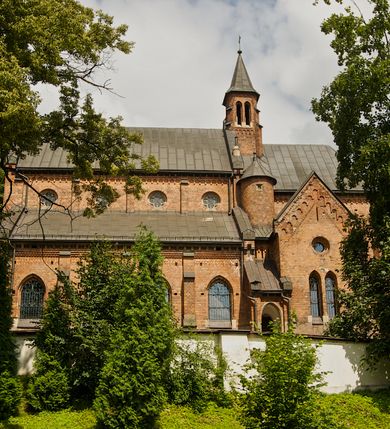 Zdjęcie nr 7: Murowana z cegły, orientowana, trzynawowa bazylika emporowa z prezbiterium zamkniętym trójbocznie. Do jednej czwartej wysokości murów lico kamienne, całość obiega cokół. Fasada dwukondygnacyjna, trójosiowa; oś środkowa wysunięta przed lico muru. Podziały pionowe tworzą dwuuskokowe przypory, poziome gzyms w połowie wysokości osi środkowej. Na osi portal ostrołukowy, uskokowy, flankowany filarami wspartymi na wysokich cokołach. W filarach fragmenty laski. Powyżej wsporniki podtrzymujące wąską archiwoltę otoczoną fryzem arkadowym. Nad otworem drzwiowym tympanon o zarysie łuku ostrego. W zwieńczeniu trójkątny przyczółek, którego ramiona spływają na konsolki oparte na filarach; całość wieńczy krzyż. Ponad portalem dwa okna w uskokowym obramieniu zakończonym łukiem ostrym. Ponad nimi okrągłe okno, wyżej kamienny kartusz z herbem fundatorki. Fasadę wieńczy ząbkowanie i fryz arkadowy. W skrajnych osiach okna ostrołukowe. W dolnym, lewym rogu osi środkowej data: MCMV. Podziały ścian nawy bocznej stanowią trójskokowe przypory; pomiędzy nimi okna ostrołukowe w uskokowych obramieniach. Ponad oknami ząbkowanie, profilowany architraw, fryz i gzyms wsparty na kroksztynach. W partii nawy głównej podział ścian tworzą małe przypory, pomiędzy którymi znajdują się okrągłe okna, ponad nimi fryz arkadowy. W zwieńczeniu kroksztyny. W ścianach zakrystii dwa wąskie, ostrołukowe okna i jedno okrągłe w profilowanych obramieniach. W trójkątnym zwieńczeniu fryz arkadowy ujęty w dwa pasy ząbkowania. Przy zachodniej ścianie południowej zakrystii znajduje się boczne wejście otwarte dwoma ostrołukowymi arkadami, wspartymi na filarze. W górnej partii ozdobione fryzem arkadowym, ząbkowaniem i kroksztynami. Pomiędzy nawą boczną a południową zakrystią okrągła wieżyczka z dwoma kwadratowymi otworami okiennymi. Strona północna analogiczna do południowej, oprócz pomieszczenia między nawą a zakrystią i portalu w pomieszczeniu przy kruchcie. Pomieszczenie z wejściem pomocniczym od strony zachodniej Od północy wąskie okno zamknięte łukiem półkolistym, w narożach ryzality zwieńczone konsolkami z fryzem arkadowym i gzymsem pomiędzy. Portal kamienny, ustawiony na czterech stopniach, ostrołukowy, zwieńczony trójkątnym przyczółkiem z ramionami spływającymi na profilowane konsole. Prezbiterium opięte czterema przyporami dwuuskokowymi. W ścianie wschodniej płycina zakończona łukiem ostrym. W zwieńczeniu fryz arkadowy i gzyms wsparty na kroksztynach. Pomiędzy nawą główną, a prezbiterium wieżyczka na sygnaturkę na planie kwadratu ze ściętymi narożami, przy których znajdują się dwuuskokowe przypory. We wszystkich ścianach wieżyczki po dwa okna ostrołukowe z parapetem, pod nim fryz arkadowy. Ściany wieńczy pas kostkowania. Nawa główna, część prezbiterium i zakrystie przykrywa dach dwuspadowy, z zakończeniu prezbiterium dach powtarza kształt prezbiterium. Nawy boczne nakryte dachem pulpitowym, wieżyczka dachem stożkowym, wieżyczka na sygnaturkę ostrosłupowym ze ściętymi krawędziami. Wszystkie dachy blaszane.Najcenniejszy wyposażenie wnętrza stanowią trzy późnobarokowe ołtarze z 1710 roku (w głównym obraz św. Marii Magdaleny z początku XVIII wieku w sukience z 1709 roku,) ambona z 1711 oraz chrzcielnica czarnomarmurowa z 1751 roku.