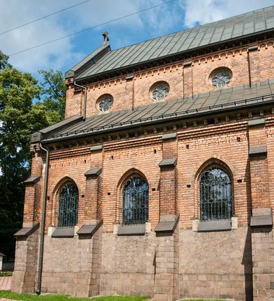 Zdjęcie nr 4: Murowana z cegły, orientowana, trzynawowa bazylika emporowa z prezbiterium zamkniętym trójbocznie. Do jednej czwartej wysokości murów lico kamienne, całość obiega cokół. Fasada dwukondygnacyjna, trójosiowa; oś środkowa wysunięta przed lico muru. Podziały pionowe tworzą dwuuskokowe przypory, poziome gzyms w połowie wysokości osi środkowej. Na osi portal ostrołukowy, uskokowy, flankowany filarami wspartymi na wysokich cokołach. W filarach fragmenty laski. Powyżej wsporniki podtrzymujące wąską archiwoltę otoczoną fryzem arkadowym. Nad otworem drzwiowym tympanon o zarysie łuku ostrego. W zwieńczeniu trójkątny przyczółek, którego ramiona spływają na konsolki oparte na filarach; całość wieńczy krzyż. Ponad portalem dwa okna w uskokowym obramieniu zakończonym łukiem ostrym. Ponad nimi okrągłe okno, wyżej kamienny kartusz z herbem fundatorki. Fasadę wieńczy ząbkowanie i fryz arkadowy. W skrajnych osiach okna ostrołukowe. W dolnym, lewym rogu osi środkowej data: MCMV. Podziały ścian nawy bocznej stanowią trójskokowe przypory; pomiędzy nimi okna ostrołukowe w uskokowych obramieniach. Ponad oknami ząbkowanie, profilowany architraw, fryz i gzyms wsparty na kroksztynach. W partii nawy głównej podział ścian tworzą małe przypory, pomiędzy którymi znajdują się okrągłe okna, ponad nimi fryz arkadowy. W zwieńczeniu kroksztyny. W ścianach zakrystii dwa wąskie, ostrołukowe okna i jedno okrągłe w profilowanych obramieniach. W trójkątnym zwieńczeniu fryz arkadowy ujęty w dwa pasy ząbkowania. Przy zachodniej ścianie południowej zakrystii znajduje się boczne wejście otwarte dwoma ostrołukowymi arkadami, wspartymi na filarze. W górnej partii ozdobione fryzem arkadowym, ząbkowaniem i kroksztynami. Pomiędzy nawą boczną a południową zakrystią okrągła wieżyczka z dwoma kwadratowymi otworami okiennymi. Strona północna analogiczna do południowej, oprócz pomieszczenia między nawą a zakrystią i portalu w pomieszczeniu przy kruchcie. Pomieszczenie z wejściem pomocniczym od strony zachodniej Od północy wąskie okno zamknięte łukiem półkolistym, w narożach ryzality zwieńczone konsolkami z fryzem arkadowym i gzymsem pomiędzy. Portal kamienny, ustawiony na czterech stopniach, ostrołukowy, zwieńczony trójkątnym przyczółkiem z ramionami spływającymi na profilowane konsole. Prezbiterium opięte czterema przyporami dwuuskokowymi. W ścianie wschodniej płycina zakończona łukiem ostrym. W zwieńczeniu fryz arkadowy i gzyms wsparty na kroksztynach. Pomiędzy nawą główną, a prezbiterium wieżyczka na sygnaturkę na planie kwadratu ze ściętymi narożami, przy których znajdują się dwuuskokowe przypory. We wszystkich ścianach wieżyczki po dwa okna ostrołukowe z parapetem, pod nim fryz arkadowy. Ściany wieńczy pas kostkowania. Nawa główna, część prezbiterium i zakrystie przykrywa dach dwuspadowy, z zakończeniu prezbiterium dach powtarza kształt prezbiterium. Nawy boczne nakryte dachem pulpitowym, wieżyczka dachem stożkowym, wieżyczka na sygnaturkę ostrosłupowym ze ściętymi krawędziami. Wszystkie dachy blaszane.Najcenniejszy wyposażenie wnętrza stanowią trzy późnobarokowe ołtarze z 1710 roku (w głównym obraz św. Marii Magdaleny z początku XVIII wieku w sukience z 1709 roku,) ambona z 1711 oraz chrzcielnica czarnomarmurowa z 1751 roku.