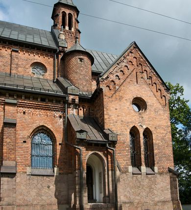 Zdjęcie nr 5: Murowana z cegły, orientowana, trzynawowa bazylika emporowa z prezbiterium zamkniętym trójbocznie. Do jednej czwartej wysokości murów lico kamienne, całość obiega cokół. Fasada dwukondygnacyjna, trójosiowa; oś środkowa wysunięta przed lico muru. Podziały pionowe tworzą dwuuskokowe przypory, poziome gzyms w połowie wysokości osi środkowej. Na osi portal ostrołukowy, uskokowy, flankowany filarami wspartymi na wysokich cokołach. W filarach fragmenty laski. Powyżej wsporniki podtrzymujące wąską archiwoltę otoczoną fryzem arkadowym. Nad otworem drzwiowym tympanon o zarysie łuku ostrego. W zwieńczeniu trójkątny przyczółek, którego ramiona spływają na konsolki oparte na filarach; całość wieńczy krzyż. Ponad portalem dwa okna w uskokowym obramieniu zakończonym łukiem ostrym. Ponad nimi okrągłe okno, wyżej kamienny kartusz z herbem fundatorki. Fasadę wieńczy ząbkowanie i fryz arkadowy. W skrajnych osiach okna ostrołukowe. W dolnym, lewym rogu osi środkowej data: MCMV. Podziały ścian nawy bocznej stanowią trójskokowe przypory; pomiędzy nimi okna ostrołukowe w uskokowych obramieniach. Ponad oknami ząbkowanie, profilowany architraw, fryz i gzyms wsparty na kroksztynach. W partii nawy głównej podział ścian tworzą małe przypory, pomiędzy którymi znajdują się okrągłe okna, ponad nimi fryz arkadowy. W zwieńczeniu kroksztyny. W ścianach zakrystii dwa wąskie, ostrołukowe okna i jedno okrągłe w profilowanych obramieniach. W trójkątnym zwieńczeniu fryz arkadowy ujęty w dwa pasy ząbkowania. Przy zachodniej ścianie południowej zakrystii znajduje się boczne wejście otwarte dwoma ostrołukowymi arkadami, wspartymi na filarze. W górnej partii ozdobione fryzem arkadowym, ząbkowaniem i kroksztynami. Pomiędzy nawą boczną a południową zakrystią okrągła wieżyczka z dwoma kwadratowymi otworami okiennymi. Strona północna analogiczna do południowej, oprócz pomieszczenia między nawą a zakrystią i portalu w pomieszczeniu przy kruchcie. Pomieszczenie z wejściem pomocniczym od strony zachodniej Od północy wąskie okno zamknięte łukiem półkolistym, w narożach ryzality zwieńczone konsolkami z fryzem arkadowym i gzymsem pomiędzy. Portal kamienny, ustawiony na czterech stopniach, ostrołukowy, zwieńczony trójkątnym przyczółkiem z ramionami spływającymi na profilowane konsole. Prezbiterium opięte czterema przyporami dwuuskokowymi. W ścianie wschodniej płycina zakończona łukiem ostrym. W zwieńczeniu fryz arkadowy i gzyms wsparty na kroksztynach. Pomiędzy nawą główną, a prezbiterium wieżyczka na sygnaturkę na planie kwadratu ze ściętymi narożami, przy których znajdują się dwuuskokowe przypory. We wszystkich ścianach wieżyczki po dwa okna ostrołukowe z parapetem, pod nim fryz arkadowy. Ściany wieńczy pas kostkowania. Nawa główna, część prezbiterium i zakrystie przykrywa dach dwuspadowy, z zakończeniu prezbiterium dach powtarza kształt prezbiterium. Nawy boczne nakryte dachem pulpitowym, wieżyczka dachem stożkowym, wieżyczka na sygnaturkę ostrosłupowym ze ściętymi krawędziami. Wszystkie dachy blaszane.Najcenniejszy wyposażenie wnętrza stanowią trzy późnobarokowe ołtarze z 1710 roku (w głównym obraz św. Marii Magdaleny z początku XVIII wieku w sukience z 1709 roku,) ambona z 1711 oraz chrzcielnica czarnomarmurowa z 1751 roku.
