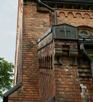 Zdjęcie nr 10: Murowana z cegły, orientowana, trzynawowa bazylika emporowa z prezbiterium zamkniętym trójbocznie. Do jednej czwartej wysokości murów lico kamienne, całość obiega cokół. Fasada dwukondygnacyjna, trójosiowa; oś środkowa wysunięta przed lico muru. Podziały pionowe tworzą dwuuskokowe przypory, poziome gzyms w połowie wysokości osi środkowej. Na osi portal ostrołukowy, uskokowy, flankowany filarami wspartymi na wysokich cokołach. W filarach fragmenty laski. Powyżej wsporniki podtrzymujące wąską archiwoltę otoczoną fryzem arkadowym. Nad otworem drzwiowym tympanon o zarysie łuku ostrego. W zwieńczeniu trójkątny przyczółek, którego ramiona spływają na konsolki oparte na filarach; całość wieńczy krzyż. Ponad portalem dwa okna w uskokowym obramieniu zakończonym łukiem ostrym. Ponad nimi okrągłe okno, wyżej kamienny kartusz z herbem fundatorki. Fasadę wieńczy ząbkowanie i fryz arkadowy. W skrajnych osiach okna ostrołukowe. W dolnym, lewym rogu osi środkowej data: MCMV. Podziały ścian nawy bocznej stanowią trójskokowe przypory; pomiędzy nimi okna ostrołukowe w uskokowych obramieniach. Ponad oknami ząbkowanie, profilowany architraw, fryz i gzyms wsparty na kroksztynach. W partii nawy głównej podział ścian tworzą małe przypory, pomiędzy którymi znajdują się okrągłe okna, ponad nimi fryz arkadowy. W zwieńczeniu kroksztyny. W ścianach zakrystii dwa wąskie, ostrołukowe okna i jedno okrągłe w profilowanych obramieniach. W trójkątnym zwieńczeniu fryz arkadowy ujęty w dwa pasy ząbkowania. Przy zachodniej ścianie południowej zakrystii znajduje się boczne wejście otwarte dwoma ostrołukowymi arkadami, wspartymi na filarze. W górnej partii ozdobione fryzem arkadowym, ząbkowaniem i kroksztynami. Pomiędzy nawą boczną a południową zakrystią okrągła wieżyczka z dwoma kwadratowymi otworami okiennymi. Strona północna analogiczna do południowej, oprócz pomieszczenia między nawą a zakrystią i portalu w pomieszczeniu przy kruchcie. Pomieszczenie z wejściem pomocniczym od strony zachodniej Od północy wąskie okno zamknięte łukiem półkolistym, w narożach ryzality zwieńczone konsolkami z fryzem arkadowym i gzymsem pomiędzy. Portal kamienny, ustawiony na czterech stopniach, ostrołukowy, zwieńczony trójkątnym przyczółkiem z ramionami spływającymi na profilowane konsole. Prezbiterium opięte czterema przyporami dwuuskokowymi. W ścianie wschodniej płycina zakończona łukiem ostrym. W zwieńczeniu fryz arkadowy i gzyms wsparty na kroksztynach. Pomiędzy nawą główną, a prezbiterium wieżyczka na sygnaturkę na planie kwadratu ze ściętymi narożami, przy których znajdują się dwuuskokowe przypory. We wszystkich ścianach wieżyczki po dwa okna ostrołukowe z parapetem, pod nim fryz arkadowy. Ściany wieńczy pas kostkowania. Nawa główna, część prezbiterium i zakrystie przykrywa dach dwuspadowy, z zakończeniu prezbiterium dach powtarza kształt prezbiterium. Nawy boczne nakryte dachem pulpitowym, wieżyczka dachem stożkowym, wieżyczka na sygnaturkę ostrosłupowym ze ściętymi krawędziami. Wszystkie dachy blaszane.Najcenniejszy wyposażenie wnętrza stanowią trzy późnobarokowe ołtarze z 1710 roku (w głównym obraz św. Marii Magdaleny z początku XVIII wieku w sukience z 1709 roku,) ambona z 1711 oraz chrzcielnica czarnomarmurowa z 1751 roku.