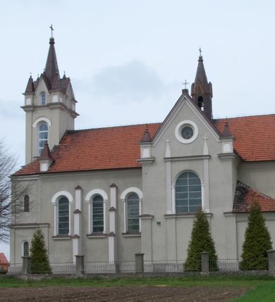 Zdjęcie nr 6: Kościół na planie krzyża łacińskiego, jednonawowy, pięcioprzęsłowy, z transeptem i jednoprzęsłowym prezbiterium zakończonym wielobocznie. Ramiona transeptu jednoprzęsłowe, o wysokości nawy, zamknięte prostymi ścianami. W narożnikach pomiędzy prezbiterium i ramionami transeptu dwa prostokątne aneksy mieszczące zakrystię i skarbiec. Prezbiterium i ramiona transeptu oddzielone od nawy wydatnymi półfilarami przechodzącymi bezpośrednio w gurty sklepienne. Prezbiterium od absydy oddziela arkada tęczowa wsparta na dostawionych do węgarów kolumnach kompozytowych. Sklepienie nad skrzyżowaniem naw krzyżowe, nad pozostałymi przęsłami nawy kolebkowe o przekroju koszowym, nad ramionami transeptu krzyżowe (ostrołukowe), w absydzie ćwierćsferyczne z lunetami. Otwory okienne prostokątne, zamknięte półkoliście, rozglifione do wewnątrz; trzy pary w nawie, dwa na ścianach zamykających ramiona transeptu. Ponad oknami w transepcie dodatkowo po jednym okrągłym oknie wypełnionym rozetą. W prezbiterium okna w kształcie wydłużonego prostokąta o smukłych proporcjach zamkniętego półkoliście, pomiędzy nimi para regularnie rozmieszczonych okien owalnych.  W zachodnim przęśle nawy murowany trójprzęsłowy chór muzyczny wsparty na parze ośmiobocznych filarów z cokołami, a pod ścianami na parze półfilarów. Balustrada o prostej dekoracji płycinowej. Podniebie chóru podzielone belkami na trzy kasetony, pośrodku których kwadratowe płyciny. Fasada kościoła dwukondygnacyjna, trójosiowa przechodząca w czworoboczną wieżę. Ściany rozczłonkowane lizenami, kondygnacje oddzielone profilowanym gzymsem. W części środkowej wejście zamknięte łukiem półkolistym, z dwuspadowym drewnianym daszkiem, wyżej prostokątne okno zamknięte półkoliście. W polach bocznych mniejsze, prostokątne okna zamknięte półkoliście. Wieża o narożach ujętych lizenami, podtrzymującymi gzyms, nakryta ozdobnym zwieńczeniem z czterema wieżyczkami w narożach, pomiędzy którymi trójkątne szczyciki nad oknami i ostrosłupowy hełm zakończony krzyżem. Ściany boczne nawy i transeptu ujęte uskokowymi przyporami. Ściany zamykające ramiona transeptu podzielone na dwie strefy, z których dolna ujęta lizenami, górna wypełniona oknem w ozdobnym obramieniu. Dachy dwuspadowe, kryte dachówką. Na skrzyżowaniu naw wieloboczna, drewniana wieżyczka na sygnaturkę nakryta ostrosłupowym hełmem pokrytym blachą.

