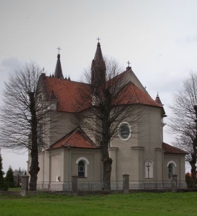 Zdjęcie nr 11: Kościół na planie krzyża łacińskiego, jednonawowy, pięcioprzęsłowy, z transeptem i jednoprzęsłowym prezbiterium zakończonym wielobocznie. Ramiona transeptu jednoprzęsłowe, o wysokości nawy, zamknięte prostymi ścianami. W narożnikach pomiędzy prezbiterium i ramionami transeptu dwa prostokątne aneksy mieszczące zakrystię i skarbiec. Prezbiterium i ramiona transeptu oddzielone od nawy wydatnymi półfilarami przechodzącymi bezpośrednio w gurty sklepienne. Prezbiterium od absydy oddziela arkada tęczowa wsparta na dostawionych do węgarów kolumnach kompozytowych. Sklepienie nad skrzyżowaniem naw krzyżowe, nad pozostałymi przęsłami nawy kolebkowe o przekroju koszowym, nad ramionami transeptu krzyżowe (ostrołukowe), w absydzie ćwierćsferyczne z lunetami. Otwory okienne prostokątne, zamknięte półkoliście, rozglifione do wewnątrz; trzy pary w nawie, dwa na ścianach zamykających ramiona transeptu. Ponad oknami w transepcie dodatkowo po jednym okrągłym oknie wypełnionym rozetą. W prezbiterium okna w kształcie wydłużonego prostokąta o smukłych proporcjach zamkniętego półkoliście, pomiędzy nimi para regularnie rozmieszczonych okien owalnych.  W zachodnim przęśle nawy murowany trójprzęsłowy chór muzyczny wsparty na parze ośmiobocznych filarów z cokołami, a pod ścianami na parze półfilarów. Balustrada o prostej dekoracji płycinowej. Podniebie chóru podzielone belkami na trzy kasetony, pośrodku których kwadratowe płyciny. Fasada kościoła dwukondygnacyjna, trójosiowa przechodząca w czworoboczną wieżę. Ściany rozczłonkowane lizenami, kondygnacje oddzielone profilowanym gzymsem. W części środkowej wejście zamknięte łukiem półkolistym, z dwuspadowym drewnianym daszkiem, wyżej prostokątne okno zamknięte półkoliście. W polach bocznych mniejsze, prostokątne okna zamknięte półkoliście. Wieża o narożach ujętych lizenami, podtrzymującymi gzyms, nakryta ozdobnym zwieńczeniem z czterema wieżyczkami w narożach, pomiędzy którymi trójkątne szczyciki nad oknami i ostrosłupowy hełm zakończony krzyżem. Ściany boczne nawy i transeptu ujęte uskokowymi przyporami. Ściany zamykające ramiona transeptu podzielone na dwie strefy, z których dolna ujęta lizenami, górna wypełniona oknem w ozdobnym obramieniu. Dachy dwuspadowe, kryte dachówką. Na skrzyżowaniu naw wieloboczna, drewniana wieżyczka na sygnaturkę nakryta ostrosłupowym hełmem pokrytym blachą.

