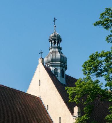 Zdjęcie nr 3: Budynek orientowany, jednonawowy. Prostokątna nawa jest szersza i znacznie wyższa, oddzielona od prezbiterium za pomocą ściany tarczowej z ostrołukową arkadą tęczową. Przy prezbiterium od północy zakrystia na planie prostokąta i taki sam skarbczyk, od południa niewielka, prostokątna kruchta. Przy nawie od południa podłużna kaplica Matki Boskiej Szkaplerznej (1741) z kwadratową kruchtą od zachodu; od północy kaplica Matki Boskiej Bolesnej na planie półokręgu z obejściem (1919-1932, projektu Bogdana Tretera). Prezbiterium sklepione krzyżowo-żebrowo, korpus sześciodzielnie, z gurtami. 
Okna nawy i kaplicy południowej ostrołukowe; w zwieńczeniu zakrystii jedno okno okrągłe; w kaplicy południowej okna zamknięte półkoliście, w kopule lukarny z eliptycznymi otworami okiennymi. 
Główne wejście od zachodu, ostrołukowe, drugie przez kruchtę od północy, w kształcie stojącego prostokąta. Portal z prezbiterium do zakrystii kamienny, profilowany zamknięty ściętym trójliściem (XV/XVI w.); portal z kruchty północnej do kaplicy kamienny, ostrołukowy, profilowany i fazowany, nad nim późnogotycka tarcza z herbem Nieczuja. Nad zewnętrznym, ostrołukowym portalem do kruchty północnej herb Korab i insygnia biskupa Jakuba Zadzika, pochodzące prawdopodobnie z dawnej bramy przejazdowej obok katedry w Kielcach. 
Na zewnątrz budynek opięty przyporami o zmiennym profilu. Elewacje, z wyjątkiem wschodniej ściany prezbiterium, tynkowane. Fasada zamknięta wysokim, trójkątnym szczytem, trójosiowa. W osi środkowej kamienny, ostrołukowy portal. W osiach bocznych ostrołukowe okna. Narożniki ujęte modelowanymi w tynku lizenami oraz przyporami. Powyżej na ich osiach prostopadłościenne sterczyny zwieńczone krzyżami. Elewacja wschodnia o analogicznym układzie, ceglana, nietynkowana, ujęta skośnie ustawionymi przyporami, jednoosiowa. W osi szeroka, jednouskokowa przypora z kamienną płyciną mieszczącą krucyfiks w dolnej części i analogiczną, mniejszą z kamienną figurą św. Piotra na tle okna powyżej. Na ścianie szczytowej cegły ułożone w jodełkę, w górnej części ostrołukowa, uskokowa płycina. Na zwieńczeniu wyryty napis „RENO/VATUM / A(NNO) D(OMINI)/ 1928”.  Elewacja północna z dobudowanymi na całej długości zakrystią, skarbczykiem i kaplicą. Elewacja południowa tynkowana, w części prezbiterium dwuosiowa; w narożniku pomiędzy prezbiterium a nawą niewielka kruchta. Do korpusu dobudowana kaplica – z tynkowanymi elewacjami o osiach podkreślonych lizenami, zróżnicowanymi kolorystycznie. Dach nad korpusem nawowym i prezbiterium dwuspadowy, nad zakrystią i skarbczykiem dachy pulpitowe –  kryte dachówką. Kaplica południowa nakryta kopułą z lunetami i latarnią – kryta blachą. Wieżyczka na sygnaturkę o formach barokowych z latarnią.