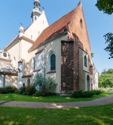 Zdjęcie nr 14: Budynek orientowany, jednonawowy. Prostokątna nawa jest szersza i znacznie wyższa, oddzielona od prezbiterium za pomocą ściany tarczowej z ostrołukową arkadą tęczową. Przy prezbiterium od północy zakrystia na planie prostokąta i taki sam skarbczyk, od południa niewielka, prostokątna kruchta. Przy nawie od południa podłużna kaplica Matki Boskiej Szkaplerznej (1741) z kwadratową kruchtą od zachodu; od północy kaplica Matki Boskiej Bolesnej na planie półokręgu z obejściem (1919-1932, projektu Bogdana Tretera). Prezbiterium sklepione krzyżowo-żebrowo, korpus sześciodzielnie, z gurtami. 
Okna nawy i kaplicy południowej ostrołukowe; w zwieńczeniu zakrystii jedno okno okrągłe; w kaplicy południowej okna zamknięte półkoliście, w kopule lukarny z eliptycznymi otworami okiennymi. 
Główne wejście od zachodu, ostrołukowe, drugie przez kruchtę od północy, w kształcie stojącego prostokąta. Portal z prezbiterium do zakrystii kamienny, profilowany zamknięty ściętym trójliściem (XV/XVI w.); portal z kruchty północnej do kaplicy kamienny, ostrołukowy, profilowany i fazowany, nad nim późnogotycka tarcza z herbem Nieczuja. Nad zewnętrznym, ostrołukowym portalem do kruchty północnej herb Korab i insygnia biskupa Jakuba Zadzika, pochodzące prawdopodobnie z dawnej bramy przejazdowej obok katedry w Kielcach. 
Na zewnątrz budynek opięty przyporami o zmiennym profilu. Elewacje, z wyjątkiem wschodniej ściany prezbiterium, tynkowane. Fasada zamknięta wysokim, trójkątnym szczytem, trójosiowa. W osi środkowej kamienny, ostrołukowy portal. W osiach bocznych ostrołukowe okna. Narożniki ujęte modelowanymi w tynku lizenami oraz przyporami. Powyżej na ich osiach prostopadłościenne sterczyny zwieńczone krzyżami. Elewacja wschodnia o analogicznym układzie, ceglana, nietynkowana, ujęta skośnie ustawionymi przyporami, jednoosiowa. W osi szeroka, jednouskokowa przypora z kamienną płyciną mieszczącą krucyfiks w dolnej części i analogiczną, mniejszą z kamienną figurą św. Piotra na tle okna powyżej. Na ścianie szczytowej cegły ułożone w jodełkę, w górnej części ostrołukowa, uskokowa płycina. Na zwieńczeniu wyryty napis „RENO/VATUM / A(NNO) D(OMINI)/ 1928”.  Elewacja północna z dobudowanymi na całej długości zakrystią, skarbczykiem i kaplicą. Elewacja południowa tynkowana, w części prezbiterium dwuosiowa; w narożniku pomiędzy prezbiterium a nawą niewielka kruchta. Do korpusu dobudowana kaplica – z tynkowanymi elewacjami o osiach podkreślonych lizenami, zróżnicowanymi kolorystycznie. Dach nad korpusem nawowym i prezbiterium dwuspadowy, nad zakrystią i skarbczykiem dachy pulpitowe –  kryte dachówką. Kaplica południowa nakryta kopułą z lunetami i latarnią – kryta blachą. Wieżyczka na sygnaturkę o formach barokowych z latarnią.