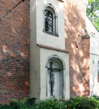 Zdjęcie nr 16: Budynek orientowany, jednonawowy. Prostokątna nawa jest szersza i znacznie wyższa, oddzielona od prezbiterium za pomocą ściany tarczowej z ostrołukową arkadą tęczową. Przy prezbiterium od północy zakrystia na planie prostokąta i taki sam skarbczyk, od południa niewielka, prostokątna kruchta. Przy nawie od południa podłużna kaplica Matki Boskiej Szkaplerznej (1741) z kwadratową kruchtą od zachodu; od północy kaplica Matki Boskiej Bolesnej na planie półokręgu z obejściem (1919-1932, projektu Bogdana Tretera). Prezbiterium sklepione krzyżowo-żebrowo, korpus sześciodzielnie, z gurtami. 
Okna nawy i kaplicy południowej ostrołukowe; w zwieńczeniu zakrystii jedno okno okrągłe; w kaplicy południowej okna zamknięte półkoliście, w kopule lukarny z eliptycznymi otworami okiennymi. 
Główne wejście od zachodu, ostrołukowe, drugie przez kruchtę od północy, w kształcie stojącego prostokąta. Portal z prezbiterium do zakrystii kamienny, profilowany zamknięty ściętym trójliściem (XV/XVI w.); portal z kruchty północnej do kaplicy kamienny, ostrołukowy, profilowany i fazowany, nad nim późnogotycka tarcza z herbem Nieczuja. Nad zewnętrznym, ostrołukowym portalem do kruchty północnej herb Korab i insygnia biskupa Jakuba Zadzika, pochodzące prawdopodobnie z dawnej bramy przejazdowej obok katedry w Kielcach. 
Na zewnątrz budynek opięty przyporami o zmiennym profilu. Elewacje, z wyjątkiem wschodniej ściany prezbiterium, tynkowane. Fasada zamknięta wysokim, trójkątnym szczytem, trójosiowa. W osi środkowej kamienny, ostrołukowy portal. W osiach bocznych ostrołukowe okna. Narożniki ujęte modelowanymi w tynku lizenami oraz przyporami. Powyżej na ich osiach prostopadłościenne sterczyny zwieńczone krzyżami. Elewacja wschodnia o analogicznym układzie, ceglana, nietynkowana, ujęta skośnie ustawionymi przyporami, jednoosiowa. W osi szeroka, jednouskokowa przypora z kamienną płyciną mieszczącą krucyfiks w dolnej części i analogiczną, mniejszą z kamienną figurą św. Piotra na tle okna powyżej. Na ścianie szczytowej cegły ułożone w jodełkę, w górnej części ostrołukowa, uskokowa płycina. Na zwieńczeniu wyryty napis „RENO/VATUM / A(NNO) D(OMINI)/ 1928”.  Elewacja północna z dobudowanymi na całej długości zakrystią, skarbczykiem i kaplicą. Elewacja południowa tynkowana, w części prezbiterium dwuosiowa; w narożniku pomiędzy prezbiterium a nawą niewielka kruchta. Do korpusu dobudowana kaplica – z tynkowanymi elewacjami o osiach podkreślonych lizenami, zróżnicowanymi kolorystycznie. Dach nad korpusem nawowym i prezbiterium dwuspadowy, nad zakrystią i skarbczykiem dachy pulpitowe –  kryte dachówką. Kaplica południowa nakryta kopułą z lunetami i latarnią – kryta blachą. Wieżyczka na sygnaturkę o formach barokowych z latarnią.