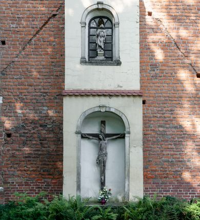 Zdjęcie nr 15: Budynek orientowany, jednonawowy. Prostokątna nawa jest szersza i znacznie wyższa, oddzielona od prezbiterium za pomocą ściany tarczowej z ostrołukową arkadą tęczową. Przy prezbiterium od północy zakrystia na planie prostokąta i taki sam skarbczyk, od południa niewielka, prostokątna kruchta. Przy nawie od południa podłużna kaplica Matki Boskiej Szkaplerznej (1741) z kwadratową kruchtą od zachodu; od północy kaplica Matki Boskiej Bolesnej na planie półokręgu z obejściem (1919-1932, projektu Bogdana Tretera). Prezbiterium sklepione krzyżowo-żebrowo, korpus sześciodzielnie, z gurtami. 
Okna nawy i kaplicy południowej ostrołukowe; w zwieńczeniu zakrystii jedno okno okrągłe; w kaplicy południowej okna zamknięte półkoliście, w kopule lukarny z eliptycznymi otworami okiennymi. 
Główne wejście od zachodu, ostrołukowe, drugie przez kruchtę od północy, w kształcie stojącego prostokąta. Portal z prezbiterium do zakrystii kamienny, profilowany zamknięty ściętym trójliściem (XV/XVI w.); portal z kruchty północnej do kaplicy kamienny, ostrołukowy, profilowany i fazowany, nad nim późnogotycka tarcza z herbem Nieczuja. Nad zewnętrznym, ostrołukowym portalem do kruchty północnej herb Korab i insygnia biskupa Jakuba Zadzika, pochodzące prawdopodobnie z dawnej bramy przejazdowej obok katedry w Kielcach. 
Na zewnątrz budynek opięty przyporami o zmiennym profilu. Elewacje, z wyjątkiem wschodniej ściany prezbiterium, tynkowane. Fasada zamknięta wysokim, trójkątnym szczytem, trójosiowa. W osi środkowej kamienny, ostrołukowy portal. W osiach bocznych ostrołukowe okna. Narożniki ujęte modelowanymi w tynku lizenami oraz przyporami. Powyżej na ich osiach prostopadłościenne sterczyny zwieńczone krzyżami. Elewacja wschodnia o analogicznym układzie, ceglana, nietynkowana, ujęta skośnie ustawionymi przyporami, jednoosiowa. W osi szeroka, jednouskokowa przypora z kamienną płyciną mieszczącą krucyfiks w dolnej części i analogiczną, mniejszą z kamienną figurą św. Piotra na tle okna powyżej. Na ścianie szczytowej cegły ułożone w jodełkę, w górnej części ostrołukowa, uskokowa płycina. Na zwieńczeniu wyryty napis „RENO/VATUM / A(NNO) D(OMINI)/ 1928”.  Elewacja północna z dobudowanymi na całej długości zakrystią, skarbczykiem i kaplicą. Elewacja południowa tynkowana, w części prezbiterium dwuosiowa; w narożniku pomiędzy prezbiterium a nawą niewielka kruchta. Do korpusu dobudowana kaplica – z tynkowanymi elewacjami o osiach podkreślonych lizenami, zróżnicowanymi kolorystycznie. Dach nad korpusem nawowym i prezbiterium dwuspadowy, nad zakrystią i skarbczykiem dachy pulpitowe –  kryte dachówką. Kaplica południowa nakryta kopułą z lunetami i latarnią – kryta blachą. Wieżyczka na sygnaturkę o formach barokowych z latarnią.