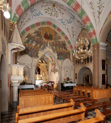 Zdjęcie nr 23: Budynek orientowany, jednonawowy. Prostokątna nawa jest szersza i znacznie wyższa, oddzielona od prezbiterium za pomocą ściany tarczowej z ostrołukową arkadą tęczową. Przy prezbiterium od północy zakrystia na planie prostokąta i taki sam skarbczyk, od południa niewielka, prostokątna kruchta. Przy nawie od południa podłużna kaplica Matki Boskiej Szkaplerznej (1741) z kwadratową kruchtą od zachodu; od północy kaplica Matki Boskiej Bolesnej na planie półokręgu z obejściem (1919-1932, projektu Bogdana Tretera). Prezbiterium sklepione krzyżowo-żebrowo, korpus sześciodzielnie, z gurtami. 
Okna nawy i kaplicy południowej ostrołukowe; w zwieńczeniu zakrystii jedno okno okrągłe; w kaplicy południowej okna zamknięte półkoliście, w kopule lukarny z eliptycznymi otworami okiennymi. 
Główne wejście od zachodu, ostrołukowe, drugie przez kruchtę od północy, w kształcie stojącego prostokąta. Portal z prezbiterium do zakrystii kamienny, profilowany zamknięty ściętym trójliściem (XV/XVI w.); portal z kruchty północnej do kaplicy kamienny, ostrołukowy, profilowany i fazowany, nad nim późnogotycka tarcza z herbem Nieczuja. Nad zewnętrznym, ostrołukowym portalem do kruchty północnej herb Korab i insygnia biskupa Jakuba Zadzika, pochodzące prawdopodobnie z dawnej bramy przejazdowej obok katedry w Kielcach. 
Na zewnątrz budynek opięty przyporami o zmiennym profilu. Elewacje, z wyjątkiem wschodniej ściany prezbiterium, tynkowane. Fasada zamknięta wysokim, trójkątnym szczytem, trójosiowa. W osi środkowej kamienny, ostrołukowy portal. W osiach bocznych ostrołukowe okna. Narożniki ujęte modelowanymi w tynku lizenami oraz przyporami. Powyżej na ich osiach prostopadłościenne sterczyny zwieńczone krzyżami. Elewacja wschodnia o analogicznym układzie, ceglana, nietynkowana, ujęta skośnie ustawionymi przyporami, jednoosiowa. W osi szeroka, jednouskokowa przypora z kamienną płyciną mieszczącą krucyfiks w dolnej części i analogiczną, mniejszą z kamienną figurą św. Piotra na tle okna powyżej. Na ścianie szczytowej cegły ułożone w jodełkę, w górnej części ostrołukowa, uskokowa płycina. Na zwieńczeniu wyryty napis „RENO/VATUM / A(NNO) D(OMINI)/ 1928”.  Elewacja północna z dobudowanymi na całej długości zakrystią, skarbczykiem i kaplicą. Elewacja południowa tynkowana, w części prezbiterium dwuosiowa; w narożniku pomiędzy prezbiterium a nawą niewielka kruchta. Do korpusu dobudowana kaplica – z tynkowanymi elewacjami o osiach podkreślonych lizenami, zróżnicowanymi kolorystycznie. Dach nad korpusem nawowym i prezbiterium dwuspadowy, nad zakrystią i skarbczykiem dachy pulpitowe –  kryte dachówką. Kaplica południowa nakryta kopułą z lunetami i latarnią – kryta blachą. Wieżyczka na sygnaturkę o formach barokowych z latarnią.