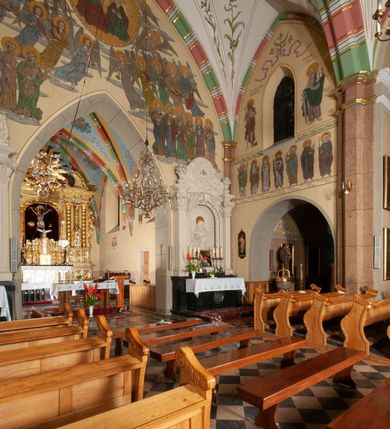 Zdjęcie nr 27: Budynek orientowany, jednonawowy. Prostokątna nawa jest szersza i znacznie wyższa, oddzielona od prezbiterium za pomocą ściany tarczowej z ostrołukową arkadą tęczową. Przy prezbiterium od północy zakrystia na planie prostokąta i taki sam skarbczyk, od południa niewielka, prostokątna kruchta. Przy nawie od południa podłużna kaplica Matki Boskiej Szkaplerznej (1741) z kwadratową kruchtą od zachodu; od północy kaplica Matki Boskiej Bolesnej na planie półokręgu z obejściem (1919-1932, projektu Bogdana Tretera). Prezbiterium sklepione krzyżowo-żebrowo, korpus sześciodzielnie, z gurtami. 
Okna nawy i kaplicy południowej ostrołukowe; w zwieńczeniu zakrystii jedno okno okrągłe; w kaplicy południowej okna zamknięte półkoliście, w kopule lukarny z eliptycznymi otworami okiennymi. 
Główne wejście od zachodu, ostrołukowe, drugie przez kruchtę od północy, w kształcie stojącego prostokąta. Portal z prezbiterium do zakrystii kamienny, profilowany zamknięty ściętym trójliściem (XV/XVI w.); portal z kruchty północnej do kaplicy kamienny, ostrołukowy, profilowany i fazowany, nad nim późnogotycka tarcza z herbem Nieczuja. Nad zewnętrznym, ostrołukowym portalem do kruchty północnej herb Korab i insygnia biskupa Jakuba Zadzika, pochodzące prawdopodobnie z dawnej bramy przejazdowej obok katedry w Kielcach. 
Na zewnątrz budynek opięty przyporami o zmiennym profilu. Elewacje, z wyjątkiem wschodniej ściany prezbiterium, tynkowane. Fasada zamknięta wysokim, trójkątnym szczytem, trójosiowa. W osi środkowej kamienny, ostrołukowy portal. W osiach bocznych ostrołukowe okna. Narożniki ujęte modelowanymi w tynku lizenami oraz przyporami. Powyżej na ich osiach prostopadłościenne sterczyny zwieńczone krzyżami. Elewacja wschodnia o analogicznym układzie, ceglana, nietynkowana, ujęta skośnie ustawionymi przyporami, jednoosiowa. W osi szeroka, jednouskokowa przypora z kamienną płyciną mieszczącą krucyfiks w dolnej części i analogiczną, mniejszą z kamienną figurą św. Piotra na tle okna powyżej. Na ścianie szczytowej cegły ułożone w jodełkę, w górnej części ostrołukowa, uskokowa płycina. Na zwieńczeniu wyryty napis „RENO/VATUM / A(NNO) D(OMINI)/ 1928”.  Elewacja północna z dobudowanymi na całej długości zakrystią, skarbczykiem i kaplicą. Elewacja południowa tynkowana, w części prezbiterium dwuosiowa; w narożniku pomiędzy prezbiterium a nawą niewielka kruchta. Do korpusu dobudowana kaplica – z tynkowanymi elewacjami o osiach podkreślonych lizenami, zróżnicowanymi kolorystycznie. Dach nad korpusem nawowym i prezbiterium dwuspadowy, nad zakrystią i skarbczykiem dachy pulpitowe –  kryte dachówką. Kaplica południowa nakryta kopułą z lunetami i latarnią – kryta blachą. Wieżyczka na sygnaturkę o formach barokowych z latarnią.