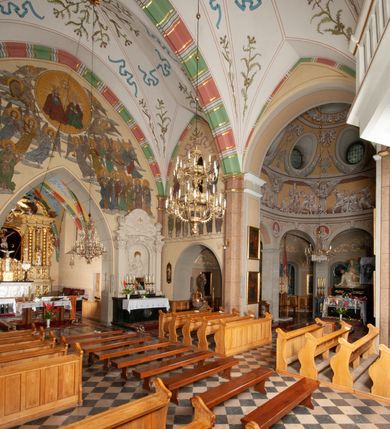 Zdjęcie nr 20: Budynek orientowany, jednonawowy. Prostokątna nawa jest szersza i znacznie wyższa, oddzielona od prezbiterium za pomocą ściany tarczowej z ostrołukową arkadą tęczową. Przy prezbiterium od północy zakrystia na planie prostokąta i taki sam skarbczyk, od południa niewielka, prostokątna kruchta. Przy nawie od południa podłużna kaplica Matki Boskiej Szkaplerznej (1741) z kwadratową kruchtą od zachodu; od północy kaplica Matki Boskiej Bolesnej na planie półokręgu z obejściem (1919-1932, projektu Bogdana Tretera). Prezbiterium sklepione krzyżowo-żebrowo, korpus sześciodzielnie, z gurtami. 
Okna nawy i kaplicy południowej ostrołukowe; w zwieńczeniu zakrystii jedno okno okrągłe; w kaplicy południowej okna zamknięte półkoliście, w kopule lukarny z eliptycznymi otworami okiennymi. 
Główne wejście od zachodu, ostrołukowe, drugie przez kruchtę od północy, w kształcie stojącego prostokąta. Portal z prezbiterium do zakrystii kamienny, profilowany zamknięty ściętym trójliściem (XV/XVI w.); portal z kruchty północnej do kaplicy kamienny, ostrołukowy, profilowany i fazowany, nad nim późnogotycka tarcza z herbem Nieczuja. Nad zewnętrznym, ostrołukowym portalem do kruchty północnej herb Korab i insygnia biskupa Jakuba Zadzika, pochodzące prawdopodobnie z dawnej bramy przejazdowej obok katedry w Kielcach. 
Na zewnątrz budynek opięty przyporami o zmiennym profilu. Elewacje, z wyjątkiem wschodniej ściany prezbiterium, tynkowane. Fasada zamknięta wysokim, trójkątnym szczytem, trójosiowa. W osi środkowej kamienny, ostrołukowy portal. W osiach bocznych ostrołukowe okna. Narożniki ujęte modelowanymi w tynku lizenami oraz przyporami. Powyżej na ich osiach prostopadłościenne sterczyny zwieńczone krzyżami. Elewacja wschodnia o analogicznym układzie, ceglana, nietynkowana, ujęta skośnie ustawionymi przyporami, jednoosiowa. W osi szeroka, jednouskokowa przypora z kamienną płyciną mieszczącą krucyfiks w dolnej części i analogiczną, mniejszą z kamienną figurą św. Piotra na tle okna powyżej. Na ścianie szczytowej cegły ułożone w jodełkę, w górnej części ostrołukowa, uskokowa płycina. Na zwieńczeniu wyryty napis „RENO/VATUM / A(NNO) D(OMINI)/ 1928”.  Elewacja północna z dobudowanymi na całej długości zakrystią, skarbczykiem i kaplicą. Elewacja południowa tynkowana, w części prezbiterium dwuosiowa; w narożniku pomiędzy prezbiterium a nawą niewielka kruchta. Do korpusu dobudowana kaplica – z tynkowanymi elewacjami o osiach podkreślonych lizenami, zróżnicowanymi kolorystycznie. Dach nad korpusem nawowym i prezbiterium dwuspadowy, nad zakrystią i skarbczykiem dachy pulpitowe –  kryte dachówką. Kaplica południowa nakryta kopułą z lunetami i latarnią – kryta blachą. Wieżyczka na sygnaturkę o formach barokowych z latarnią.