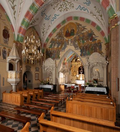 Zdjęcie nr 24: Budynek orientowany, jednonawowy. Prostokątna nawa jest szersza i znacznie wyższa, oddzielona od prezbiterium za pomocą ściany tarczowej z ostrołukową arkadą tęczową. Przy prezbiterium od północy zakrystia na planie prostokąta i taki sam skarbczyk, od południa niewielka, prostokątna kruchta. Przy nawie od południa podłużna kaplica Matki Boskiej Szkaplerznej (1741) z kwadratową kruchtą od zachodu; od północy kaplica Matki Boskiej Bolesnej na planie półokręgu z obejściem (1919-1932, projektu Bogdana Tretera). Prezbiterium sklepione krzyżowo-żebrowo, korpus sześciodzielnie, z gurtami. 
Okna nawy i kaplicy południowej ostrołukowe; w zwieńczeniu zakrystii jedno okno okrągłe; w kaplicy południowej okna zamknięte półkoliście, w kopule lukarny z eliptycznymi otworami okiennymi. 
Główne wejście od zachodu, ostrołukowe, drugie przez kruchtę od północy, w kształcie stojącego prostokąta. Portal z prezbiterium do zakrystii kamienny, profilowany zamknięty ściętym trójliściem (XV/XVI w.); portal z kruchty północnej do kaplicy kamienny, ostrołukowy, profilowany i fazowany, nad nim późnogotycka tarcza z herbem Nieczuja. Nad zewnętrznym, ostrołukowym portalem do kruchty północnej herb Korab i insygnia biskupa Jakuba Zadzika, pochodzące prawdopodobnie z dawnej bramy przejazdowej obok katedry w Kielcach. 
Na zewnątrz budynek opięty przyporami o zmiennym profilu. Elewacje, z wyjątkiem wschodniej ściany prezbiterium, tynkowane. Fasada zamknięta wysokim, trójkątnym szczytem, trójosiowa. W osi środkowej kamienny, ostrołukowy portal. W osiach bocznych ostrołukowe okna. Narożniki ujęte modelowanymi w tynku lizenami oraz przyporami. Powyżej na ich osiach prostopadłościenne sterczyny zwieńczone krzyżami. Elewacja wschodnia o analogicznym układzie, ceglana, nietynkowana, ujęta skośnie ustawionymi przyporami, jednoosiowa. W osi szeroka, jednouskokowa przypora z kamienną płyciną mieszczącą krucyfiks w dolnej części i analogiczną, mniejszą z kamienną figurą św. Piotra na tle okna powyżej. Na ścianie szczytowej cegły ułożone w jodełkę, w górnej części ostrołukowa, uskokowa płycina. Na zwieńczeniu wyryty napis „RENO/VATUM / A(NNO) D(OMINI)/ 1928”.  Elewacja północna z dobudowanymi na całej długości zakrystią, skarbczykiem i kaplicą. Elewacja południowa tynkowana, w części prezbiterium dwuosiowa; w narożniku pomiędzy prezbiterium a nawą niewielka kruchta. Do korpusu dobudowana kaplica – z tynkowanymi elewacjami o osiach podkreślonych lizenami, zróżnicowanymi kolorystycznie. Dach nad korpusem nawowym i prezbiterium dwuspadowy, nad zakrystią i skarbczykiem dachy pulpitowe –  kryte dachówką. Kaplica południowa nakryta kopułą z lunetami i latarnią – kryta blachą. Wieżyczka na sygnaturkę o formach barokowych z latarnią.