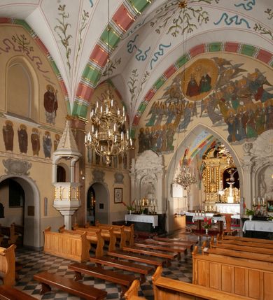 Zdjęcie nr 22: Budynek orientowany, jednonawowy. Prostokątna nawa jest szersza i znacznie wyższa, oddzielona od prezbiterium za pomocą ściany tarczowej z ostrołukową arkadą tęczową. Przy prezbiterium od północy zakrystia na planie prostokąta i taki sam skarbczyk, od południa niewielka, prostokątna kruchta. Przy nawie od południa podłużna kaplica Matki Boskiej Szkaplerznej (1741) z kwadratową kruchtą od zachodu; od północy kaplica Matki Boskiej Bolesnej na planie półokręgu z obejściem (1919-1932, projektu Bogdana Tretera). Prezbiterium sklepione krzyżowo-żebrowo, korpus sześciodzielnie, z gurtami. 
Okna nawy i kaplicy południowej ostrołukowe; w zwieńczeniu zakrystii jedno okno okrągłe; w kaplicy południowej okna zamknięte półkoliście, w kopule lukarny z eliptycznymi otworami okiennymi. 
Główne wejście od zachodu, ostrołukowe, drugie przez kruchtę od północy, w kształcie stojącego prostokąta. Portal z prezbiterium do zakrystii kamienny, profilowany zamknięty ściętym trójliściem (XV/XVI w.); portal z kruchty północnej do kaplicy kamienny, ostrołukowy, profilowany i fazowany, nad nim późnogotycka tarcza z herbem Nieczuja. Nad zewnętrznym, ostrołukowym portalem do kruchty północnej herb Korab i insygnia biskupa Jakuba Zadzika, pochodzące prawdopodobnie z dawnej bramy przejazdowej obok katedry w Kielcach. 
Na zewnątrz budynek opięty przyporami o zmiennym profilu. Elewacje, z wyjątkiem wschodniej ściany prezbiterium, tynkowane. Fasada zamknięta wysokim, trójkątnym szczytem, trójosiowa. W osi środkowej kamienny, ostrołukowy portal. W osiach bocznych ostrołukowe okna. Narożniki ujęte modelowanymi w tynku lizenami oraz przyporami. Powyżej na ich osiach prostopadłościenne sterczyny zwieńczone krzyżami. Elewacja wschodnia o analogicznym układzie, ceglana, nietynkowana, ujęta skośnie ustawionymi przyporami, jednoosiowa. W osi szeroka, jednouskokowa przypora z kamienną płyciną mieszczącą krucyfiks w dolnej części i analogiczną, mniejszą z kamienną figurą św. Piotra na tle okna powyżej. Na ścianie szczytowej cegły ułożone w jodełkę, w górnej części ostrołukowa, uskokowa płycina. Na zwieńczeniu wyryty napis „RENO/VATUM / A(NNO) D(OMINI)/ 1928”.  Elewacja północna z dobudowanymi na całej długości zakrystią, skarbczykiem i kaplicą. Elewacja południowa tynkowana, w części prezbiterium dwuosiowa; w narożniku pomiędzy prezbiterium a nawą niewielka kruchta. Do korpusu dobudowana kaplica – z tynkowanymi elewacjami o osiach podkreślonych lizenami, zróżnicowanymi kolorystycznie. Dach nad korpusem nawowym i prezbiterium dwuspadowy, nad zakrystią i skarbczykiem dachy pulpitowe –  kryte dachówką. Kaplica południowa nakryta kopułą z lunetami i latarnią – kryta blachą. Wieżyczka na sygnaturkę o formach barokowych z latarnią.