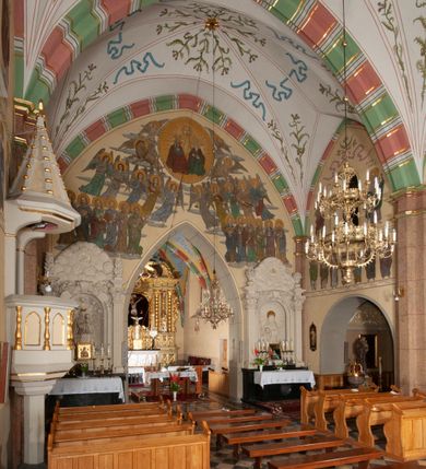 Zdjęcie nr 35: Budynek orientowany, jednonawowy. Prostokątna nawa jest szersza i znacznie wyższa, oddzielona od prezbiterium za pomocą ściany tarczowej z ostrołukową arkadą tęczową. Przy prezbiterium od północy zakrystia na planie prostokąta i taki sam skarbczyk, od południa niewielka, prostokątna kruchta. Przy nawie od południa podłużna kaplica Matki Boskiej Szkaplerznej (1741) z kwadratową kruchtą od zachodu; od północy kaplica Matki Boskiej Bolesnej na planie półokręgu z obejściem (1919-1932, projektu Bogdana Tretera). Prezbiterium sklepione krzyżowo-żebrowo, korpus sześciodzielnie, z gurtami. 
Okna nawy i kaplicy południowej ostrołukowe; w zwieńczeniu zakrystii jedno okno okrągłe; w kaplicy południowej okna zamknięte półkoliście, w kopule lukarny z eliptycznymi otworami okiennymi. 
Główne wejście od zachodu, ostrołukowe, drugie przez kruchtę od północy, w kształcie stojącego prostokąta. Portal z prezbiterium do zakrystii kamienny, profilowany zamknięty ściętym trójliściem (XV/XVI w.); portal z kruchty północnej do kaplicy kamienny, ostrołukowy, profilowany i fazowany, nad nim późnogotycka tarcza z herbem Nieczuja. Nad zewnętrznym, ostrołukowym portalem do kruchty północnej herb Korab i insygnia biskupa Jakuba Zadzika, pochodzące prawdopodobnie z dawnej bramy przejazdowej obok katedry w Kielcach. 
Na zewnątrz budynek opięty przyporami o zmiennym profilu. Elewacje, z wyjątkiem wschodniej ściany prezbiterium, tynkowane. Fasada zamknięta wysokim, trójkątnym szczytem, trójosiowa. W osi środkowej kamienny, ostrołukowy portal. W osiach bocznych ostrołukowe okna. Narożniki ujęte modelowanymi w tynku lizenami oraz przyporami. Powyżej na ich osiach prostopadłościenne sterczyny zwieńczone krzyżami. Elewacja wschodnia o analogicznym układzie, ceglana, nietynkowana, ujęta skośnie ustawionymi przyporami, jednoosiowa. W osi szeroka, jednouskokowa przypora z kamienną płyciną mieszczącą krucyfiks w dolnej części i analogiczną, mniejszą z kamienną figurą św. Piotra na tle okna powyżej. Na ścianie szczytowej cegły ułożone w jodełkę, w górnej części ostrołukowa, uskokowa płycina. Na zwieńczeniu wyryty napis „RENO/VATUM / A(NNO) D(OMINI)/ 1928”.  Elewacja północna z dobudowanymi na całej długości zakrystią, skarbczykiem i kaplicą. Elewacja południowa tynkowana, w części prezbiterium dwuosiowa; w narożniku pomiędzy prezbiterium a nawą niewielka kruchta. Do korpusu dobudowana kaplica – z tynkowanymi elewacjami o osiach podkreślonych lizenami, zróżnicowanymi kolorystycznie. Dach nad korpusem nawowym i prezbiterium dwuspadowy, nad zakrystią i skarbczykiem dachy pulpitowe –  kryte dachówką. Kaplica południowa nakryta kopułą z lunetami i latarnią – kryta blachą. Wieżyczka na sygnaturkę o formach barokowych z latarnią.