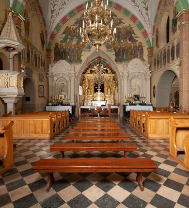 Zdjęcie nr 36: Budynek orientowany, jednonawowy. Prostokątna nawa jest szersza i znacznie wyższa, oddzielona od prezbiterium za pomocą ściany tarczowej z ostrołukową arkadą tęczową. Przy prezbiterium od północy zakrystia na planie prostokąta i taki sam skarbczyk, od południa niewielka, prostokątna kruchta. Przy nawie od południa podłużna kaplica Matki Boskiej Szkaplerznej (1741) z kwadratową kruchtą od zachodu; od północy kaplica Matki Boskiej Bolesnej na planie półokręgu z obejściem (1919-1932, projektu Bogdana Tretera). Prezbiterium sklepione krzyżowo-żebrowo, korpus sześciodzielnie, z gurtami. 
Okna nawy i kaplicy południowej ostrołukowe; w zwieńczeniu zakrystii jedno okno okrągłe; w kaplicy południowej okna zamknięte półkoliście, w kopule lukarny z eliptycznymi otworami okiennymi. 
Główne wejście od zachodu, ostrołukowe, drugie przez kruchtę od północy, w kształcie stojącego prostokąta. Portal z prezbiterium do zakrystii kamienny, profilowany zamknięty ściętym trójliściem (XV/XVI w.); portal z kruchty północnej do kaplicy kamienny, ostrołukowy, profilowany i fazowany, nad nim późnogotycka tarcza z herbem Nieczuja. Nad zewnętrznym, ostrołukowym portalem do kruchty północnej herb Korab i insygnia biskupa Jakuba Zadzika, pochodzące prawdopodobnie z dawnej bramy przejazdowej obok katedry w Kielcach. 
Na zewnątrz budynek opięty przyporami o zmiennym profilu. Elewacje, z wyjątkiem wschodniej ściany prezbiterium, tynkowane. Fasada zamknięta wysokim, trójkątnym szczytem, trójosiowa. W osi środkowej kamienny, ostrołukowy portal. W osiach bocznych ostrołukowe okna. Narożniki ujęte modelowanymi w tynku lizenami oraz przyporami. Powyżej na ich osiach prostopadłościenne sterczyny zwieńczone krzyżami. Elewacja wschodnia o analogicznym układzie, ceglana, nietynkowana, ujęta skośnie ustawionymi przyporami, jednoosiowa. W osi szeroka, jednouskokowa przypora z kamienną płyciną mieszczącą krucyfiks w dolnej części i analogiczną, mniejszą z kamienną figurą św. Piotra na tle okna powyżej. Na ścianie szczytowej cegły ułożone w jodełkę, w górnej części ostrołukowa, uskokowa płycina. Na zwieńczeniu wyryty napis „RENO/VATUM / A(NNO) D(OMINI)/ 1928”.  Elewacja północna z dobudowanymi na całej długości zakrystią, skarbczykiem i kaplicą. Elewacja południowa tynkowana, w części prezbiterium dwuosiowa; w narożniku pomiędzy prezbiterium a nawą niewielka kruchta. Do korpusu dobudowana kaplica – z tynkowanymi elewacjami o osiach podkreślonych lizenami, zróżnicowanymi kolorystycznie. Dach nad korpusem nawowym i prezbiterium dwuspadowy, nad zakrystią i skarbczykiem dachy pulpitowe –  kryte dachówką. Kaplica południowa nakryta kopułą z lunetami i latarnią – kryta blachą. Wieżyczka na sygnaturkę o formach barokowych z latarnią.