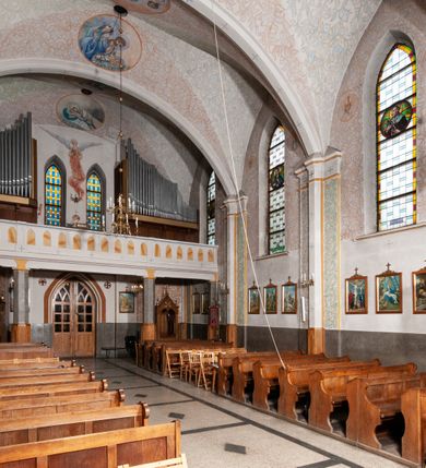 Zdjęcie nr 33: Kościół murowany z cegły, tynkowany, orientowany z odchyleniem ku północy. Zbudowany na planie krzyża łacińskiego, jednonawowy z transeptem, pięcioprzęsłowy, z jednoprzęsłowym prezbiterium zamkniętym trójbocznie. Sklepienie beczkowe spłaszczone (koszowe) na gurtach z lunetami stykającymi się wierzchołkami. W pierwszym od zachodu przęśle nawy chór muzyczny konstrukcji żelbetowej wsparty na dwóch filarach o przekroju ośmioboku i dwóch analogicznych półfilarach. Balustrada artykułowana ostrołukowymi niszami. Ściany boczne rozczłonkowane analogicznymi półfilarami, ustawionymi na tle pilastrów; proste kapitele toskańskie. Ściana tęczowa z arkadą ostrołukową, ujętą po bokach dwoma mniejszymi ostrołukowymi płycinami. Od zachodu prostokątna kruchta z dwoma ostrołukowymi otworami drzwiowymi. Mniejsza prostokątna kruchta od południa, skomunikowana z nawą kamiennym, profilowanym portalem prostokątnym. W prezbiterium od południa prostokątny otwór wejściowy do zakrystii. Okna obustronnie rozglifione, z  parapetami, o kształcie wydłużonego prostokąta, zamkniętego ostrołukowo; po trzy w ścianach bocznych nawy, trzy w prezbiterium. Dwa mniejsze w fasadzie kościoła, po jednym na ścianach bocznych kruchty zachodniej. W zamknięciu ścian transeptu, większe ostrołukowe okna z podziałami kamiennymi dzielącymi okno na dwie, mniejsze, przedzielone półfilarem, zamknięte ostrołukowo części. Kościół nakryty dachem dwuspadowym z blachy. Fasada bezwieżowa z trójkątnym szczytem. Na zewnętrznej, wschodniej ścianie prezbiterium niewielka kwadratowa płycina z inskrypcją: „KAMIEŃ / WĘGIELNY / POŚWIĘCONY / DN(IA) 21 VI 1936”.