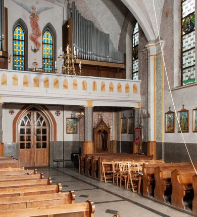 Zdjęcie nr 34: Kościół murowany z cegły, tynkowany, orientowany z odchyleniem ku północy. Zbudowany na planie krzyża łacińskiego, jednonawowy z transeptem, pięcioprzęsłowy, z jednoprzęsłowym prezbiterium zamkniętym trójbocznie. Sklepienie beczkowe spłaszczone (koszowe) na gurtach z lunetami stykającymi się wierzchołkami. W pierwszym od zachodu przęśle nawy chór muzyczny konstrukcji żelbetowej wsparty na dwóch filarach o przekroju ośmioboku i dwóch analogicznych półfilarach. Balustrada artykułowana ostrołukowymi niszami. Ściany boczne rozczłonkowane analogicznymi półfilarami, ustawionymi na tle pilastrów; proste kapitele toskańskie. Ściana tęczowa z arkadą ostrołukową, ujętą po bokach dwoma mniejszymi ostrołukowymi płycinami. Od zachodu prostokątna kruchta z dwoma ostrołukowymi otworami drzwiowymi. Mniejsza prostokątna kruchta od południa, skomunikowana z nawą kamiennym, profilowanym portalem prostokątnym. W prezbiterium od południa prostokątny otwór wejściowy do zakrystii. Okna obustronnie rozglifione, z  parapetami, o kształcie wydłużonego prostokąta, zamkniętego ostrołukowo; po trzy w ścianach bocznych nawy, trzy w prezbiterium. Dwa mniejsze w fasadzie kościoła, po jednym na ścianach bocznych kruchty zachodniej. W zamknięciu ścian transeptu, większe ostrołukowe okna z podziałami kamiennymi dzielącymi okno na dwie, mniejsze, przedzielone półfilarem, zamknięte ostrołukowo części. Kościół nakryty dachem dwuspadowym z blachy. Fasada bezwieżowa z trójkątnym szczytem. Na zewnętrznej, wschodniej ścianie prezbiterium niewielka kwadratowa płycina z inskrypcją: „KAMIEŃ / WĘGIELNY / POŚWIĘCONY / DN(IA) 21 VI 1936”.