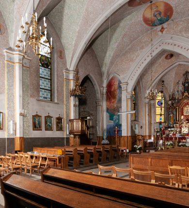 Zdjęcie nr 21: Kościół murowany z cegły, tynkowany, orientowany z odchyleniem ku północy. Zbudowany na planie krzyża łacińskiego, jednonawowy z transeptem, pięcioprzęsłowy, z jednoprzęsłowym prezbiterium zamkniętym trójbocznie. Sklepienie beczkowe spłaszczone (koszowe) na gurtach z lunetami stykającymi się wierzchołkami. W pierwszym od zachodu przęśle nawy chór muzyczny konstrukcji żelbetowej wsparty na dwóch filarach o przekroju ośmioboku i dwóch analogicznych półfilarach. Balustrada artykułowana ostrołukowymi niszami. Ściany boczne rozczłonkowane analogicznymi półfilarami, ustawionymi na tle pilastrów; proste kapitele toskańskie. Ściana tęczowa z arkadą ostrołukową, ujętą po bokach dwoma mniejszymi ostrołukowymi płycinami. Od zachodu prostokątna kruchta z dwoma ostrołukowymi otworami drzwiowymi. Mniejsza prostokątna kruchta od południa, skomunikowana z nawą kamiennym, profilowanym portalem prostokątnym. W prezbiterium od południa prostokątny otwór wejściowy do zakrystii. Okna obustronnie rozglifione, z  parapetami, o kształcie wydłużonego prostokąta, zamkniętego ostrołukowo; po trzy w ścianach bocznych nawy, trzy w prezbiterium. Dwa mniejsze w fasadzie kościoła, po jednym na ścianach bocznych kruchty zachodniej. W zamknięciu ścian transeptu, większe ostrołukowe okna z podziałami kamiennymi dzielącymi okno na dwie, mniejsze, przedzielone półfilarem, zamknięte ostrołukowo części. Kościół nakryty dachem dwuspadowym z blachy. Fasada bezwieżowa z trójkątnym szczytem. Na zewnętrznej, wschodniej ścianie prezbiterium niewielka kwadratowa płycina z inskrypcją: „KAMIEŃ / WĘGIELNY / POŚWIĘCONY / DN(IA) 21 VI 1936”.