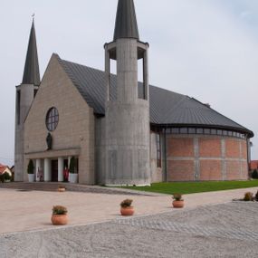 Zdjęcie nr 1: Kościół usytuowany na dużej działce o nieregularnym kształcie.  Świątynia otoczona trawnikiem, w którym wydzielono niewielkie klomby kwiatowe i ciągi komunikacyjne. Kościół orientowany, jednonawowy, jednoprzestrzenny z prezbiterium zamkniętym od zewnątrz szeroką absydą. Ściany boczne nawy od strony wschodniej założone na planie odcinka koła. Wnętrze jednoprzestrzenne, z widoczną konstrukcją otwartej więźby dachowej. Widoczne, drewniane belki wspierające się na 12 kolumnach, ustawionych w dwa rzędy, w układzie powtarzających rytm ścian. Prezbiterium na trójstopniowym wzniesieniu, oddzielone od nawy ścianą tęczową, zamknięte prostą ścianą. Od strony zachodniej chór muzyczny konstrukcji żelbetowej o pełnym, prostym parapecie, wsparty na dwóch okrągłych filarach. Po cztery pionowe okna łączące się w górnych partiach z świetlikiem obiegającym całą nawę. Mury zakończone uproszczonym gzymsem. W północno-zachodnim narożu niewielka kaplica Jana Pawła II, założona na planie koła. Fasada kościoła z trójkątną ścianą szczytową wyłożoną okładziną kamienną z umieszczonym w osi dużym okrągłym oknem, ujęta dwoma betonowymi wieżami na planie koła. W górnej części wieże z prześwitami na dzwony, nakryte strzelistymi, ostrosłupowymi dachami. W przyziemiu portyk wejściowy w formie czterech kolumn dźwigających masywny gzyms z napisem: „KOŚCIÓŁ MATKI BOSKIEJ RÓŻAŃCOWEJ”, powyżej rzeźba Madonny z Dzieciątkiem. 

