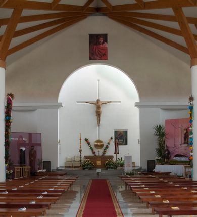 Zdjęcie nr 24: Kościół usytuowany na dużej działce o nieregularnym kształcie.  Świątynia otoczona trawnikiem, w którym wydzielono niewielkie klomby kwiatowe i ciągi komunikacyjne. Kościół orientowany, jednonawowy, jednoprzestrzenny z prezbiterium zamkniętym od zewnątrz szeroką absydą. Ściany boczne nawy od strony wschodniej założone na planie odcinka koła. Wnętrze jednoprzestrzenne, z widoczną konstrukcją otwartej więźby dachowej. Widoczne, drewniane belki wspierające się na 12 kolumnach, ustawionych w dwa rzędy, w układzie powtarzających rytm ścian. Prezbiterium na trójstopniowym wzniesieniu, oddzielone od nawy ścianą tęczową, zamknięte prostą ścianą. Od strony zachodniej chór muzyczny konstrukcji żelbetowej o pełnym, prostym parapecie, wsparty na dwóch okrągłych filarach. Po cztery pionowe okna łączące się w górnych partiach z świetlikiem obiegającym całą nawę. Mury zakończone uproszczonym gzymsem. W północno-zachodnim narożu niewielka kaplica Jana Pawła II, założona na planie koła. Fasada kościoła z trójkątną ścianą szczytową wyłożoną okładziną kamienną z umieszczonym w osi dużym okrągłym oknem, ujęta dwoma betonowymi wieżami na planie koła. W górnej części wieże z prześwitami na dzwony, nakryte strzelistymi, ostrosłupowymi dachami. W przyziemiu portyk wejściowy w formie czterech kolumn dźwigających masywny gzyms z napisem: „KOŚCIÓŁ MATKI BOSKIEJ RÓŻAŃCOWEJ”, powyżej rzeźba Madonny z Dzieciątkiem. 

