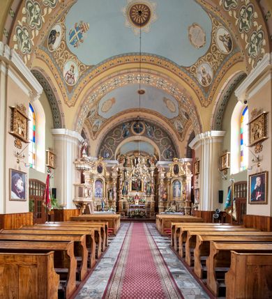 Zdjęcie nr 6: Kościół murowany, orientowany, na planie wydłużonego prostokąta, jednonawowy, trójprzęsłowy. Do prosto zamkniętego prezbiterium przylega na osi zakrystia, od północy kruchta. Ściany artykułowane wewnątrz pilastrami o profilowanych narożach, na pilastry spływają gurty sklepienia, prezbiterium węższe, sklepienie kolebkowe, od zachodu chór z niszą, w której ustawiono organy. Ściany pokrywa polichromia figuralno-ornamentalna z dominującymi kolorami żółtym i niebieskim. Między pilastrami okna w kształcie stojącego prostokąta zamkniętego półkoliście; mniejsze przy chórze. Główne drzwi od wschodu, boczne od północy. 
Fasada trójosiowa, jednokondygnacyjna, zakończona wieżą z hełmem. Osie wydzielone są parami lizen. Na osi wejście w kształcie stojącego prostokąta, powyżej ślepe okno zamknięte półkoliście, naroża zaokrąglone. Powyżej kondygnacja czworobocznej wieży, z czterech stron przeprutej oknami o wykroju jak w fasadzie, przedzielona gzymsem powyżej którego tarcze zegara. Ściany boczne kościoła artykułowane lizenami, okna umieszczone we wnękach. Nawa główna oraz kruchta nakryte dachami dwuspadowymi, prezbiterium oraz zakrystia trójspadowymi, na kalenicy nawy sześcioboczna wieżyczka na sygnaturkę; wieża pokryta dachem czterospadowym z kulą i krzyżem. 
Całe wyposażenie wnętrza pochodzi z drugiej połowy XIX lub z XX wieku, uwagę przyciągają zwłaszcza neobarokowe ołtarze. 
