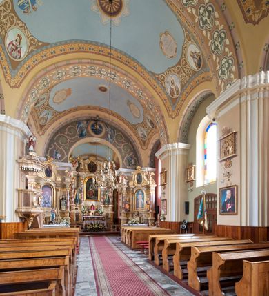 Zdjęcie nr 5: Kościół murowany, orientowany, na planie wydłużonego prostokąta, jednonawowy, trójprzęsłowy. Do prosto zamkniętego prezbiterium przylega na osi zakrystia, od północy kruchta. Ściany artykułowane wewnątrz pilastrami o profilowanych narożach, na pilastry spływają gurty sklepienia, prezbiterium węższe, sklepienie kolebkowe, od zachodu chór z niszą, w której ustawiono organy. Ściany pokrywa polichromia figuralno-ornamentalna z dominującymi kolorami żółtym i niebieskim. Między pilastrami okna w kształcie stojącego prostokąta zamkniętego półkoliście; mniejsze przy chórze. Główne drzwi od wschodu, boczne od północy. 
Fasada trójosiowa, jednokondygnacyjna, zakończona wieżą z hełmem. Osie wydzielone są parami lizen. Na osi wejście w kształcie stojącego prostokąta, powyżej ślepe okno zamknięte półkoliście, naroża zaokrąglone. Powyżej kondygnacja czworobocznej wieży, z czterech stron przeprutej oknami o wykroju jak w fasadzie, przedzielona gzymsem powyżej którego tarcze zegara. Ściany boczne kościoła artykułowane lizenami, okna umieszczone we wnękach. Nawa główna oraz kruchta nakryte dachami dwuspadowymi, prezbiterium oraz zakrystia trójspadowymi, na kalenicy nawy sześcioboczna wieżyczka na sygnaturkę; wieża pokryta dachem czterospadowym z kulą i krzyżem. 
Całe wyposażenie wnętrza pochodzi z drugiej połowy XIX lub z XX wieku, uwagę przyciągają zwłaszcza neobarokowe ołtarze. 
