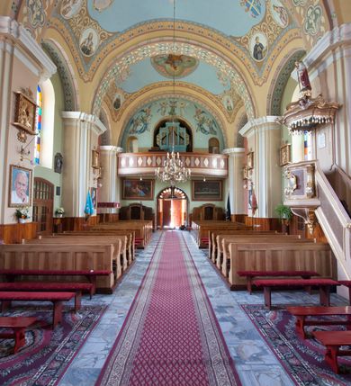 Zdjęcie nr 12: Kościół murowany, orientowany, na planie wydłużonego prostokąta, jednonawowy, trójprzęsłowy. Do prosto zamkniętego prezbiterium przylega na osi zakrystia, od północy kruchta. Ściany artykułowane wewnątrz pilastrami o profilowanych narożach, na pilastry spływają gurty sklepienia, prezbiterium węższe, sklepienie kolebkowe, od zachodu chór z niszą, w której ustawiono organy. Ściany pokrywa polichromia figuralno-ornamentalna z dominującymi kolorami żółtym i niebieskim. Między pilastrami okna w kształcie stojącego prostokąta zamkniętego półkoliście; mniejsze przy chórze. Główne drzwi od wschodu, boczne od północy. 
Fasada trójosiowa, jednokondygnacyjna, zakończona wieżą z hełmem. Osie wydzielone są parami lizen. Na osi wejście w kształcie stojącego prostokąta, powyżej ślepe okno zamknięte półkoliście, naroża zaokrąglone. Powyżej kondygnacja czworobocznej wieży, z czterech stron przeprutej oknami o wykroju jak w fasadzie, przedzielona gzymsem powyżej którego tarcze zegara. Ściany boczne kościoła artykułowane lizenami, okna umieszczone we wnękach. Nawa główna oraz kruchta nakryte dachami dwuspadowymi, prezbiterium oraz zakrystia trójspadowymi, na kalenicy nawy sześcioboczna wieżyczka na sygnaturkę; wieża pokryta dachem czterospadowym z kulą i krzyżem. 
Całe wyposażenie wnętrza pochodzi z drugiej połowy XIX lub z XX wieku, uwagę przyciągają zwłaszcza neobarokowe ołtarze. 
