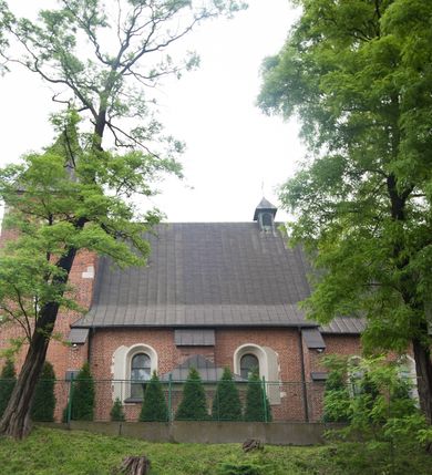 Zdjęcie nr 22: Na miejscu kościoła romańskiego, orientowany, dwunawowy, halowy; nawa południowa na rzucie prostokąta, na osi prezbiterium, dwuprzęsłowa, sklepiona kolebkowo z lunetami, na gurtach; nawa północna węższa od południowej, dwuprzęsłowa, sklepiona krzyżowo-żebrowo z kolistymi płaskorzeźbionymi zwornikami, jeden z literami ihs, drugi z literą s pod koroną. Prezbiterium prostokątne, dwuprzęsłowe, sklepione krzyżowo-żebrowo, z kolistymi zwornikami i profilowanymi wspornikami; przy nim od północy dawna zakrystia na rzucie prostokąta, sklepiona kolebkowo, otwarta do nawy wtórną arkadą, od wschodu nowa zakrystia na rzucie ośmioboku. Od zachodu przylega do nawy kwadratowa, czterokondygnacyjna wieża, z wieżyczką schodową w narożu północno-wschodnim, kruchtą w przyziemiu i chórem muzycznym na piętrze. Przy niej od północy drewniana piętrowa przybudówka mieszcząca w przyziemiu komorę bracką, na piętrze miech i kanał organowy. Przy nawie południowej od południa kwadratowa kruchta. Arkada tęczy zamknięta łukiem półkolistym, arkady do nawy północnej łukiem lekko zaostrzonym. Mury opięte przyporami, elewacje na cokole, z wzorami z zendrówki. Okna pierwotnie ostrołukowe, obustronnie rozglifione (niektóre zbarokizowane). Portale: zachodni, do kruchty pod wieżą, oraz do kruchty południowej, kamienne, prostokątne. Dachy dwuspadowe, pokryte blachą miedzianą. Zakrystia od wschodu przy prezbiterium wzniesiona na miejscu drewnianej kaplicy Ogrojcowej z XVIII wieku.