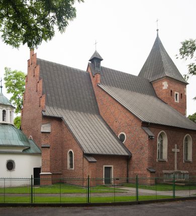 Zdjęcie nr 21: Na miejscu kościoła romańskiego, orientowany, dwunawowy, halowy; nawa południowa na rzucie prostokąta, na osi prezbiterium, dwuprzęsłowa, sklepiona kolebkowo z lunetami, na gurtach; nawa północna węższa od południowej, dwuprzęsłowa, sklepiona krzyżowo-żebrowo z kolistymi płaskorzeźbionymi zwornikami, jeden z literami ihs, drugi z literą s pod koroną. Prezbiterium prostokątne, dwuprzęsłowe, sklepione krzyżowo-żebrowo, z kolistymi zwornikami i profilowanymi wspornikami; przy nim od północy dawna zakrystia na rzucie prostokąta, sklepiona kolebkowo, otwarta do nawy wtórną arkadą, od wschodu nowa zakrystia na rzucie ośmioboku. Od zachodu przylega do nawy kwadratowa, czterokondygnacyjna wieża, z wieżyczką schodową w narożu północno-wschodnim, kruchtą w przyziemiu i chórem muzycznym na piętrze. Przy niej od północy drewniana piętrowa przybudówka mieszcząca w przyziemiu komorę bracką, na piętrze miech i kanał organowy. Przy nawie południowej od południa kwadratowa kruchta. Arkada tęczy zamknięta łukiem półkolistym, arkady do nawy północnej łukiem lekko zaostrzonym. Mury opięte przyporami, elewacje na cokole, z wzorami z zendrówki. Okna pierwotnie ostrołukowe, obustronnie rozglifione (niektóre zbarokizowane). Portale: zachodni, do kruchty pod wieżą, oraz do kruchty południowej, kamienne, prostokątne. Dachy dwuspadowe, pokryte blachą miedzianą. Zakrystia od wschodu przy prezbiterium wzniesiona na miejscu drewnianej kaplicy Ogrojcowej z XVIII wieku.