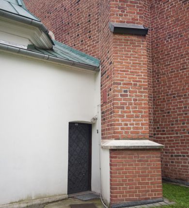 Zdjęcie nr 32: Na miejscu kościoła romańskiego, orientowany, dwunawowy, halowy; nawa południowa na rzucie prostokąta, na osi prezbiterium, dwuprzęsłowa, sklepiona kolebkowo z lunetami, na gurtach; nawa północna węższa od południowej, dwuprzęsłowa, sklepiona krzyżowo-żebrowo z kolistymi płaskorzeźbionymi zwornikami, jeden z literami ihs, drugi z literą s pod koroną. Prezbiterium prostokątne, dwuprzęsłowe, sklepione krzyżowo-żebrowo, z kolistymi zwornikami i profilowanymi wspornikami; przy nim od północy dawna zakrystia na rzucie prostokąta, sklepiona kolebkowo, otwarta do nawy wtórną arkadą, od wschodu nowa zakrystia na rzucie ośmioboku. Od zachodu przylega do nawy kwadratowa, czterokondygnacyjna wieża, z wieżyczką schodową w narożu północno-wschodnim, kruchtą w przyziemiu i chórem muzycznym na piętrze. Przy niej od północy drewniana piętrowa przybudówka mieszcząca w przyziemiu komorę bracką, na piętrze miech i kanał organowy. Przy nawie południowej od południa kwadratowa kruchta. Arkada tęczy zamknięta łukiem półkolistym, arkady do nawy północnej łukiem lekko zaostrzonym. Mury opięte przyporami, elewacje na cokole, z wzorami z zendrówki. Okna pierwotnie ostrołukowe, obustronnie rozglifione (niektóre zbarokizowane). Portale: zachodni, do kruchty pod wieżą, oraz do kruchty południowej, kamienne, prostokątne. Dachy dwuspadowe, pokryte blachą miedzianą. Zakrystia od wschodu przy prezbiterium wzniesiona na miejscu drewnianej kaplicy Ogrojcowej z XVIII wieku.