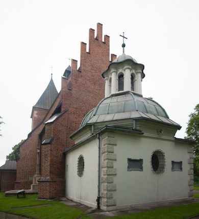 Zdjęcie nr 3: Na miejscu kościoła romańskiego, orientowany, dwunawowy, halowy; nawa południowa na rzucie prostokąta, na osi prezbiterium, dwuprzęsłowa, sklepiona kolebkowo z lunetami, na gurtach; nawa północna węższa od południowej, dwuprzęsłowa, sklepiona krzyżowo-żebrowo z kolistymi płaskorzeźbionymi zwornikami, jeden z literami ihs, drugi z literą s pod koroną. Prezbiterium prostokątne, dwuprzęsłowe, sklepione krzyżowo-żebrowo, z kolistymi zwornikami i profilowanymi wspornikami; przy nim od północy dawna zakrystia na rzucie prostokąta, sklepiona kolebkowo, otwarta do nawy wtórną arkadą, od wschodu nowa zakrystia na rzucie ośmioboku. Od zachodu przylega do nawy kwadratowa, czterokondygnacyjna wieża, z wieżyczką schodową w narożu północno-wschodnim, kruchtą w przyziemiu i chórem muzycznym na piętrze. Przy niej od północy drewniana piętrowa przybudówka mieszcząca w przyziemiu komorę bracką, na piętrze miech i kanał organowy. Przy nawie południowej od południa kwadratowa kruchta. Arkada tęczy zamknięta łukiem półkolistym, arkady do nawy północnej łukiem lekko zaostrzonym. Mury opięte przyporami, elewacje na cokole, z wzorami z zendrówki. Okna pierwotnie ostrołukowe, obustronnie rozglifione (niektóre zbarokizowane). Portale: zachodni, do kruchty pod wieżą, oraz do kruchty południowej, kamienne, prostokątne. Dachy dwuspadowe, pokryte blachą miedzianą. Zakrystia od wschodu przy prezbiterium wzniesiona na miejscu drewnianej kaplicy Ogrojcowej z XVIII wieku.