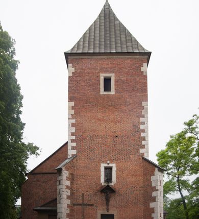 Zdjęcie nr 2: Na miejscu kościoła romańskiego, orientowany, dwunawowy, halowy; nawa południowa na rzucie prostokąta, na osi prezbiterium, dwuprzęsłowa, sklepiona kolebkowo z lunetami, na gurtach; nawa północna węższa od południowej, dwuprzęsłowa, sklepiona krzyżowo-żebrowo z kolistymi płaskorzeźbionymi zwornikami, jeden z literami ihs, drugi z literą s pod koroną. Prezbiterium prostokątne, dwuprzęsłowe, sklepione krzyżowo-żebrowo, z kolistymi zwornikami i profilowanymi wspornikami; przy nim od północy dawna zakrystia na rzucie prostokąta, sklepiona kolebkowo, otwarta do nawy wtórną arkadą, od wschodu nowa zakrystia na rzucie ośmioboku. Od zachodu przylega do nawy kwadratowa, czterokondygnacyjna wieża, z wieżyczką schodową w narożu północno-wschodnim, kruchtą w przyziemiu i chórem muzycznym na piętrze. Przy niej od północy drewniana piętrowa przybudówka mieszcząca w przyziemiu komorę bracką, na piętrze miech i kanał organowy. Przy nawie południowej od południa kwadratowa kruchta. Arkada tęczy zamknięta łukiem półkolistym, arkady do nawy północnej łukiem lekko zaostrzonym. Mury opięte przyporami, elewacje na cokole, z wzorami z zendrówki. Okna pierwotnie ostrołukowe, obustronnie rozglifione (niektóre zbarokizowane). Portale: zachodni, do kruchty pod wieżą, oraz do kruchty południowej, kamienne, prostokątne. Dachy dwuspadowe, pokryte blachą miedzianą. Zakrystia od wschodu przy prezbiterium wzniesiona na miejscu drewnianej kaplicy Ogrojcowej z XVIII wieku.