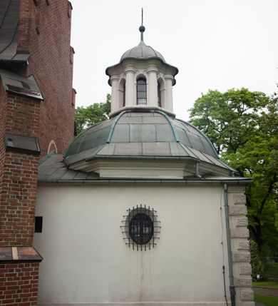 Zdjęcie nr 6: Na miejscu kościoła romańskiego, orientowany, dwunawowy, halowy; nawa południowa na rzucie prostokąta, na osi prezbiterium, dwuprzęsłowa, sklepiona kolebkowo z lunetami, na gurtach; nawa północna węższa od południowej, dwuprzęsłowa, sklepiona krzyżowo-żebrowo z kolistymi płaskorzeźbionymi zwornikami, jeden z literami ihs, drugi z literą s pod koroną. Prezbiterium prostokątne, dwuprzęsłowe, sklepione krzyżowo-żebrowo, z kolistymi zwornikami i profilowanymi wspornikami; przy nim od północy dawna zakrystia na rzucie prostokąta, sklepiona kolebkowo, otwarta do nawy wtórną arkadą, od wschodu nowa zakrystia na rzucie ośmioboku. Od zachodu przylega do nawy kwadratowa, czterokondygnacyjna wieża, z wieżyczką schodową w narożu północno-wschodnim, kruchtą w przyziemiu i chórem muzycznym na piętrze. Przy niej od północy drewniana piętrowa przybudówka mieszcząca w przyziemiu komorę bracką, na piętrze miech i kanał organowy. Przy nawie południowej od południa kwadratowa kruchta. Arkada tęczy zamknięta łukiem półkolistym, arkady do nawy północnej łukiem lekko zaostrzonym. Mury opięte przyporami, elewacje na cokole, z wzorami z zendrówki. Okna pierwotnie ostrołukowe, obustronnie rozglifione (niektóre zbarokizowane). Portale: zachodni, do kruchty pod wieżą, oraz do kruchty południowej, kamienne, prostokątne. Dachy dwuspadowe, pokryte blachą miedzianą. Zakrystia od wschodu przy prezbiterium wzniesiona na miejscu drewnianej kaplicy Ogrojcowej z XVIII wieku.