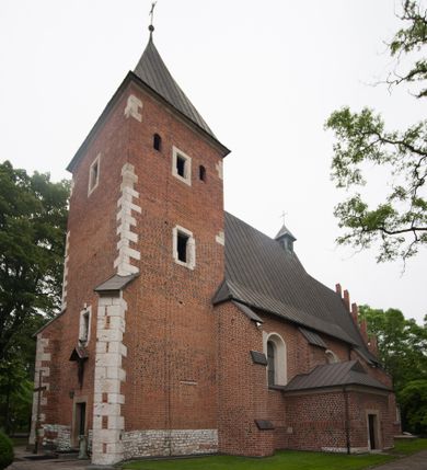 Zdjęcie nr 1: Na miejscu kościoła romańskiego, orientowany, dwunawowy, halowy; nawa południowa na rzucie prostokąta, na osi prezbiterium, dwuprzęsłowa, sklepiona kolebkowo z lunetami, na gurtach; nawa północna węższa od południowej, dwuprzęsłowa, sklepiona krzyżowo-żebrowo z kolistymi płaskorzeźbionymi zwornikami, jeden z literami ihs, drugi z literą s pod koroną. Prezbiterium prostokątne, dwuprzęsłowe, sklepione krzyżowo-żebrowo, z kolistymi zwornikami i profilowanymi wspornikami; przy nim od północy dawna zakrystia na rzucie prostokąta, sklepiona kolebkowo, otwarta do nawy wtórną arkadą, od wschodu nowa zakrystia na rzucie ośmioboku. Od zachodu przylega do nawy kwadratowa, czterokondygnacyjna wieża, z wieżyczką schodową w narożu północno-wschodnim, kruchtą w przyziemiu i chórem muzycznym na piętrze. Przy niej od północy drewniana piętrowa przybudówka mieszcząca w przyziemiu komorę bracką, na piętrze miech i kanał organowy. Przy nawie południowej od południa kwadratowa kruchta. Arkada tęczy zamknięta łukiem półkolistym, arkady do nawy północnej łukiem lekko zaostrzonym. Mury opięte przyporami, elewacje na cokole, z wzorami z zendrówki. Okna pierwotnie ostrołukowe, obustronnie rozglifione (niektóre zbarokizowane). Portale: zachodni, do kruchty pod wieżą, oraz do kruchty południowej, kamienne, prostokątne. Dachy dwuspadowe, pokryte blachą miedzianą. Zakrystia od wschodu przy prezbiterium wzniesiona na miejscu drewnianej kaplicy Ogrojcowej z XVIII wieku.